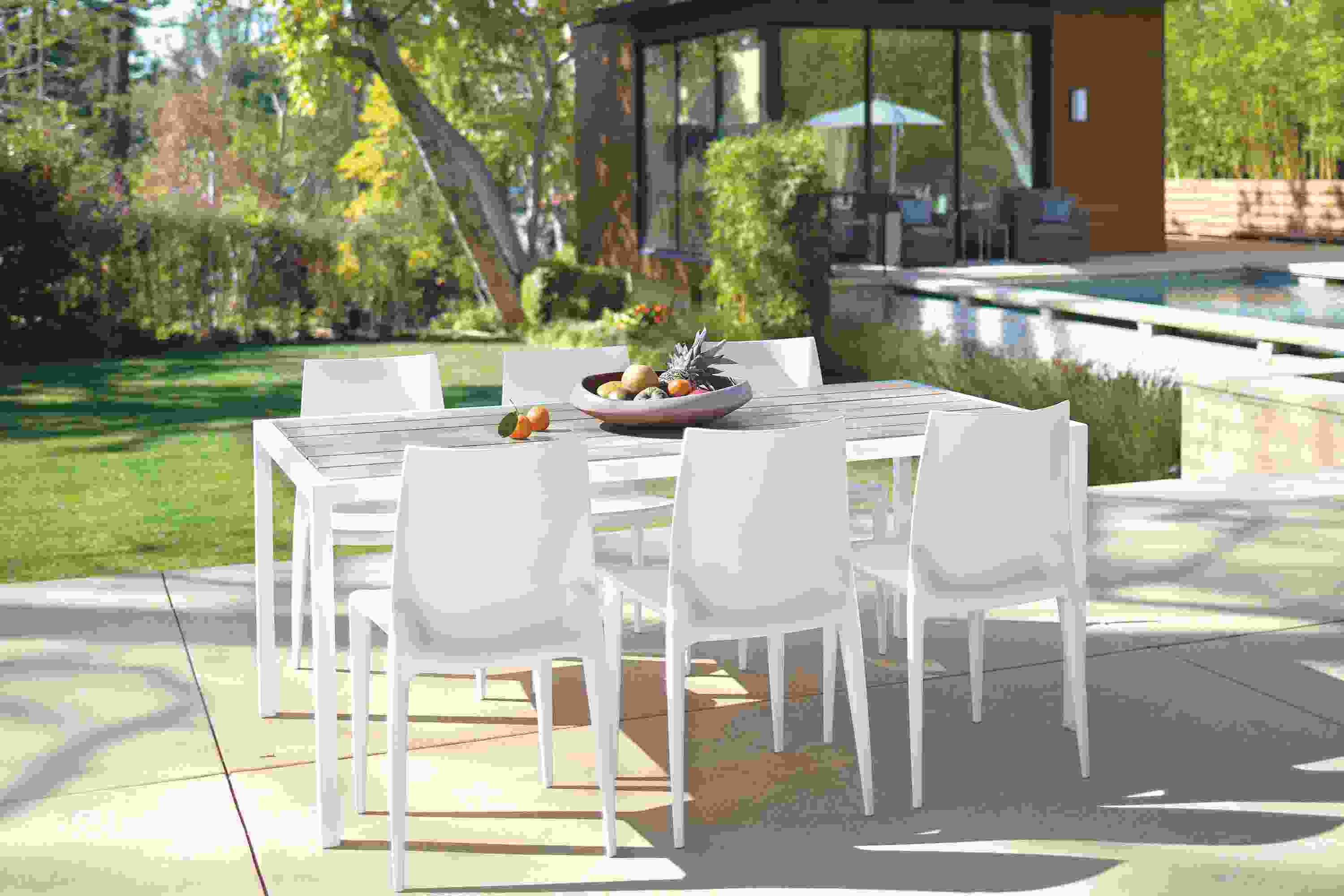 Outdoor dining space with Montego table and bench in aged thermally modified ash and 5 sabrina chairs in white.
