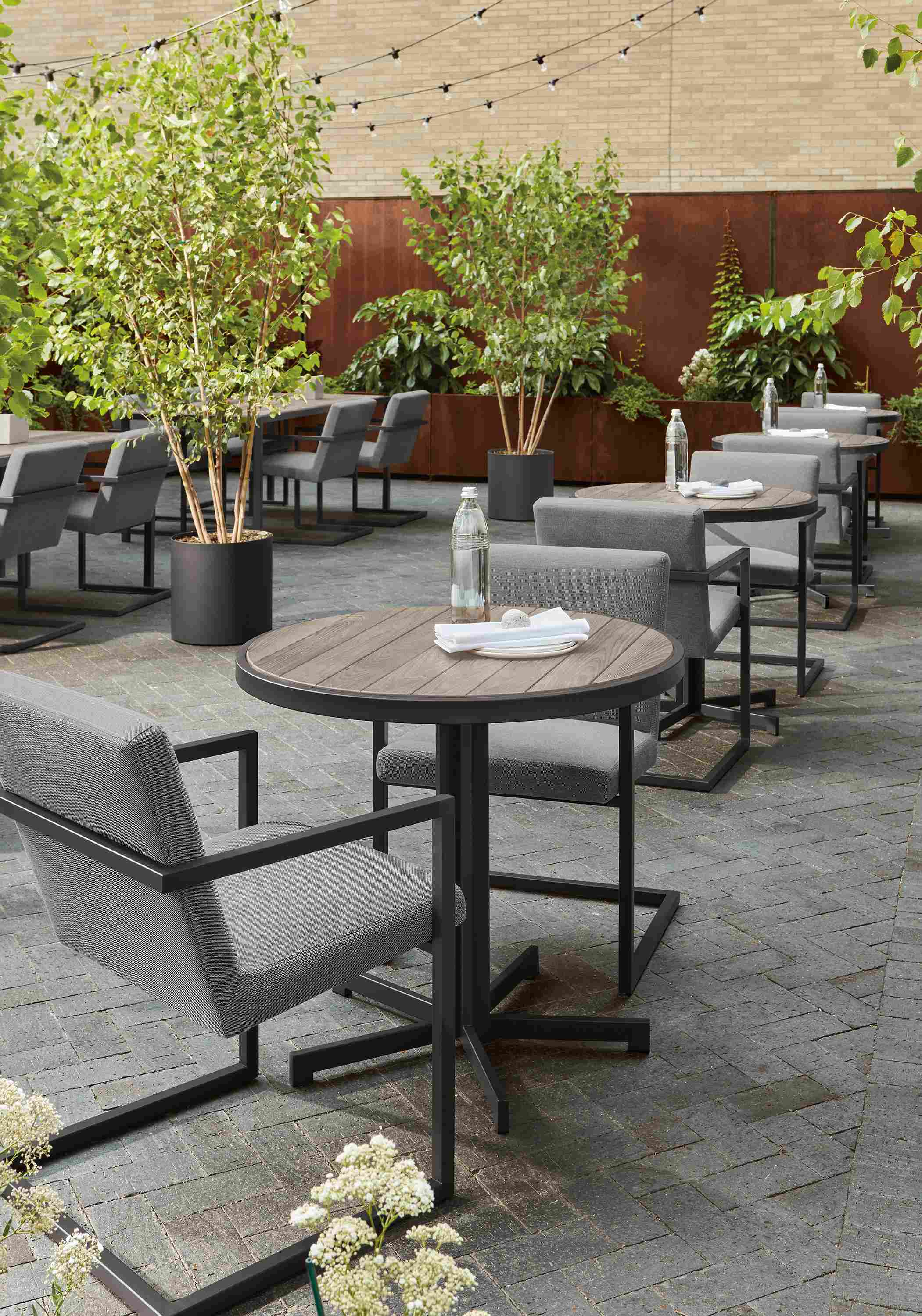 Outdoor commercial dining space with multiple montego dining tables in aged thermally modified oak and Finn chairs in Pelham Grey.
