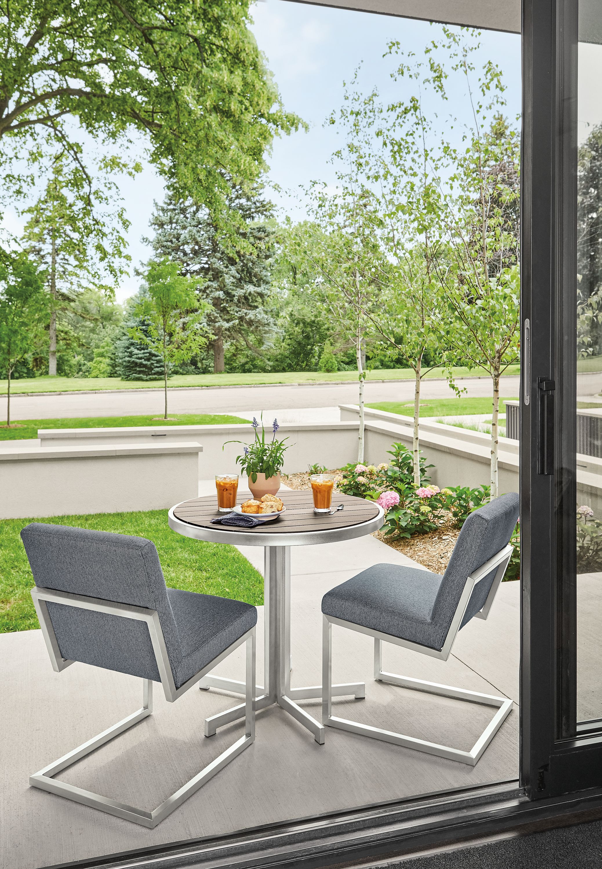 Outdoor patio with finn side chairs in mist fabric and Montego round table in aged thermally modified oak and stainless steel.