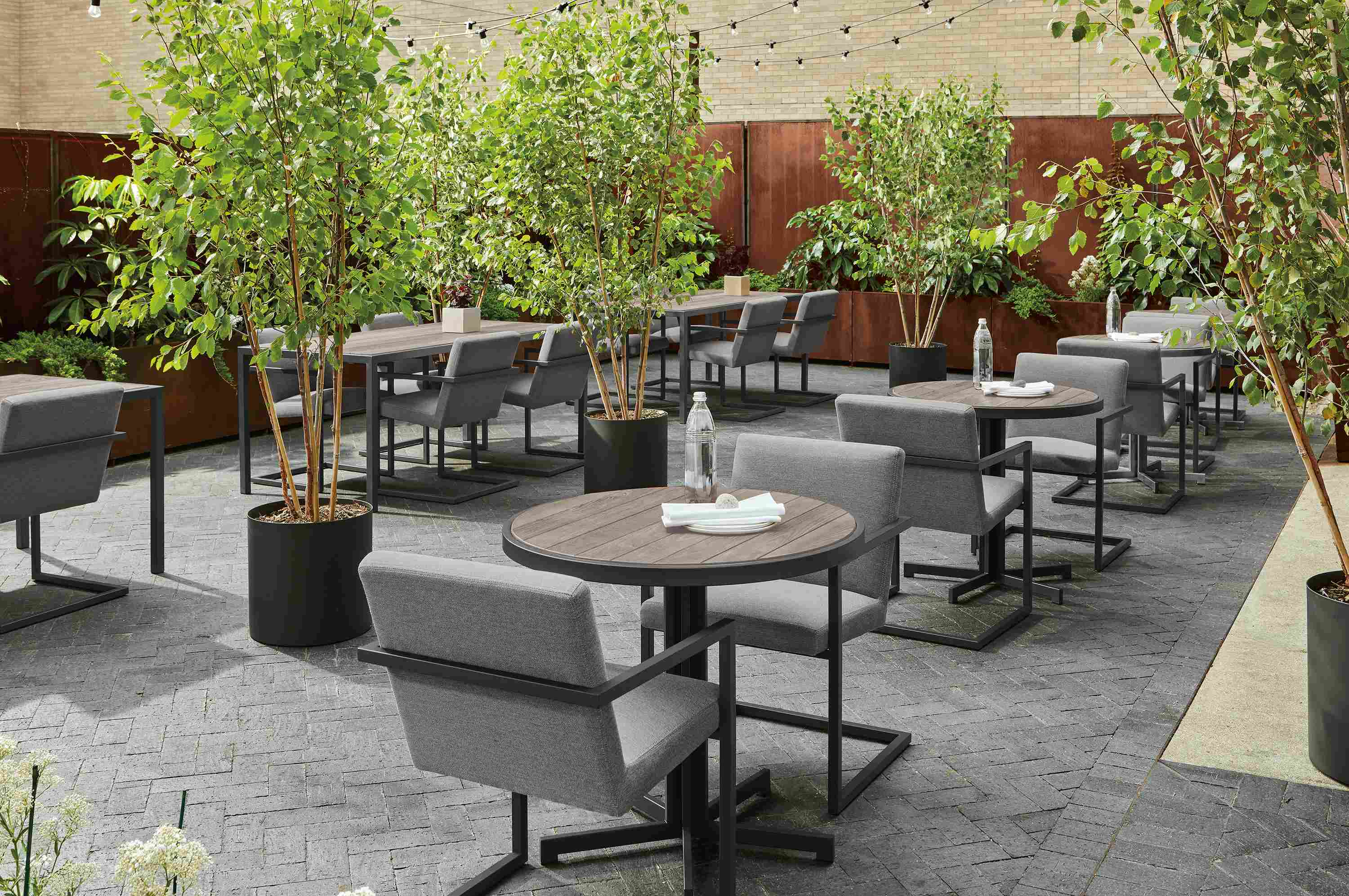 Outdoor commercial dining space with montego round and rectangular tables in aged thermally modified oak and Finn arm chairs.