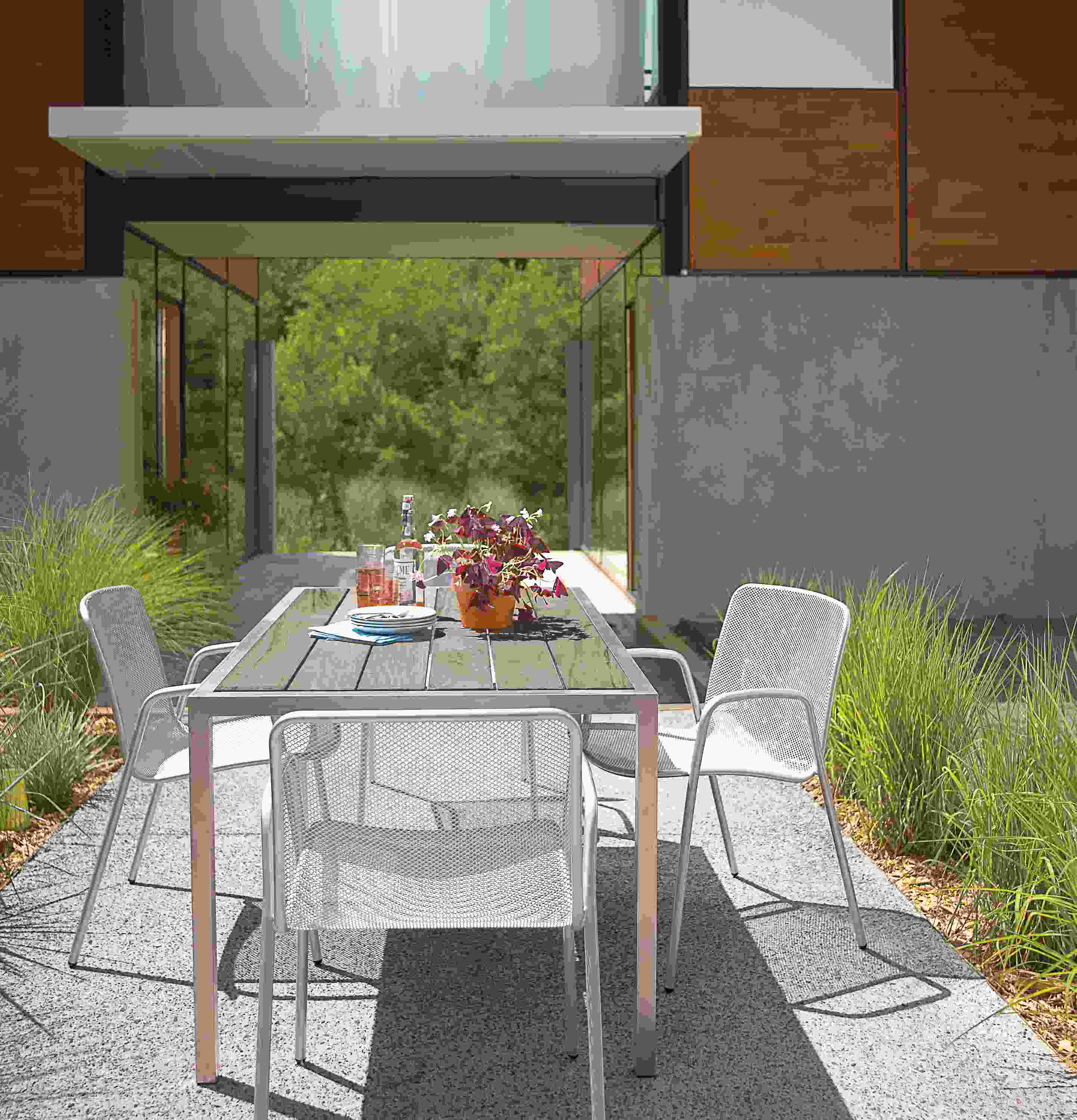Outdoor dining space with Montego 60-wide table in aged thermally modified oak and Aruba chairs in silver.