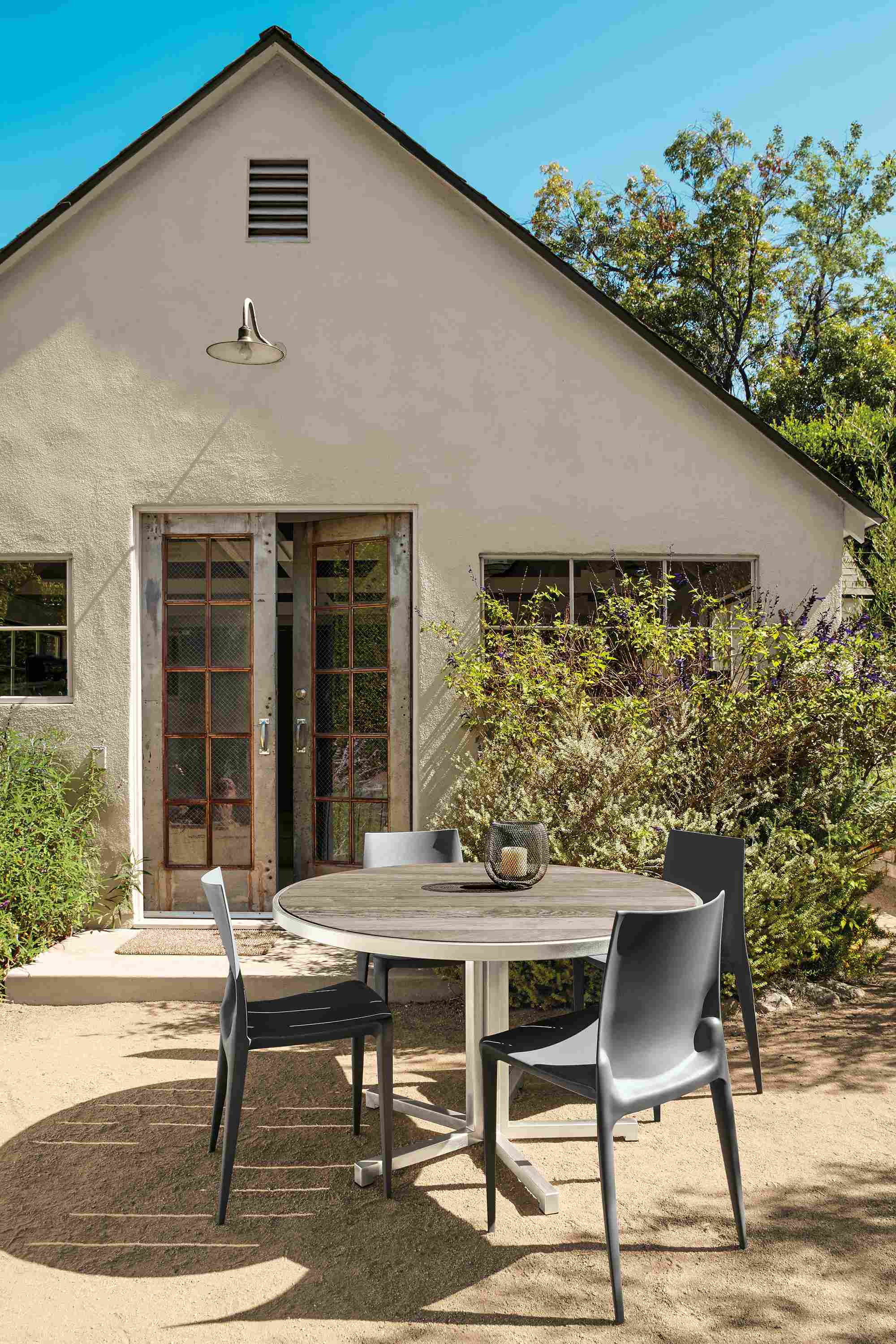 Outdoor space with montego bar table in stainless steel and 2 montego bar stools in aged thermally modified oak.