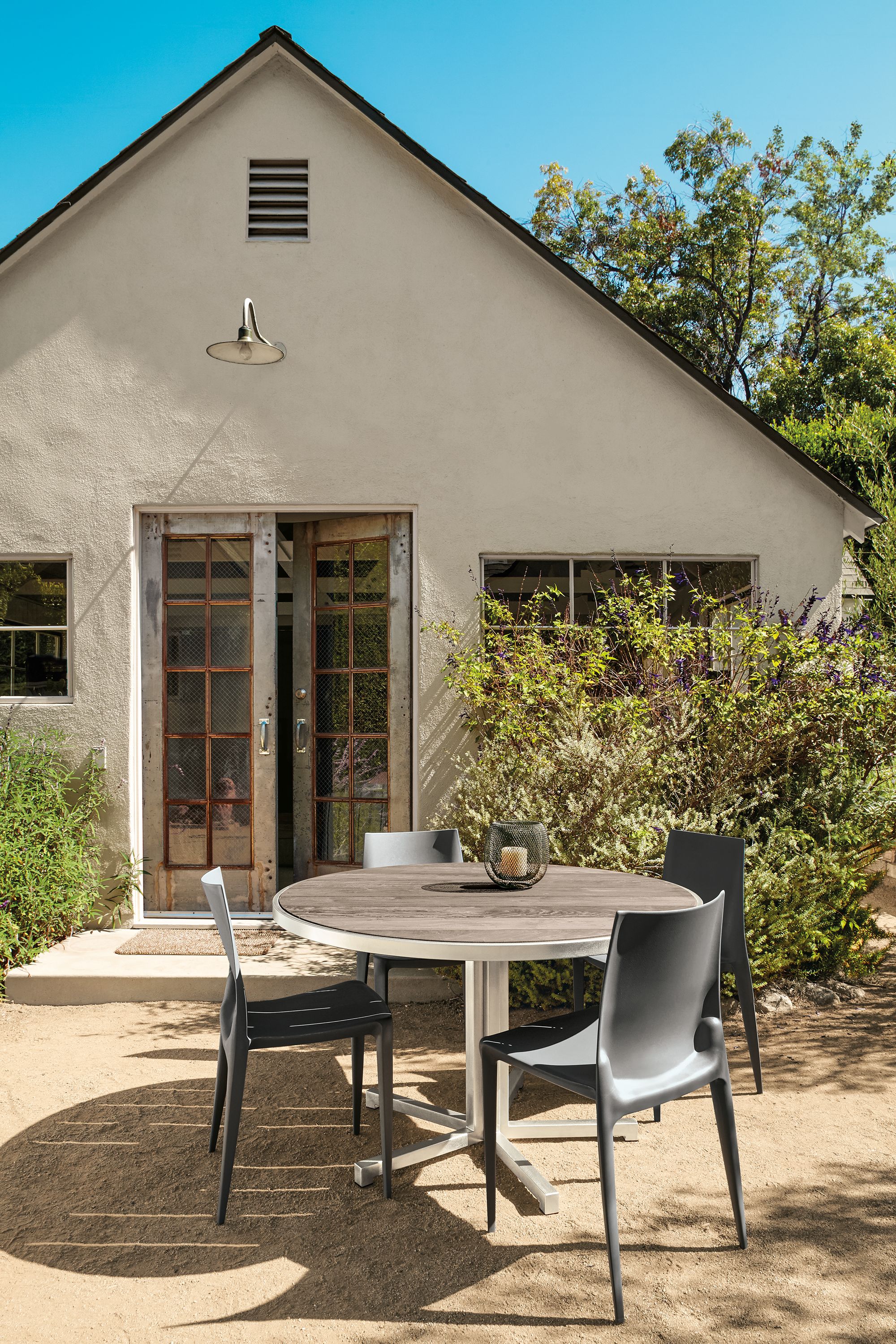 Outdoor space with montego bar table in stainless steel and 2 montego bar stools in aged thermally modified oak.