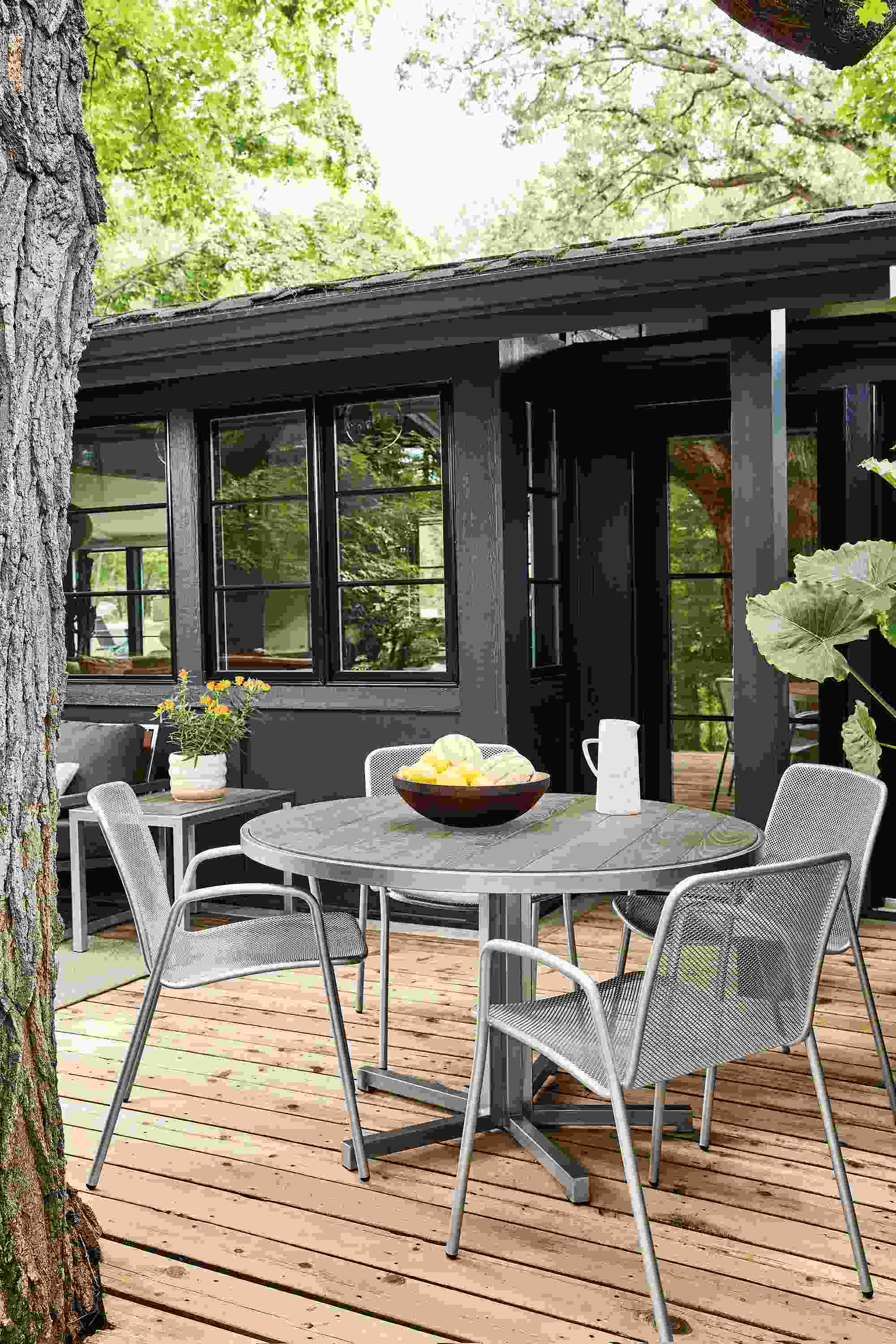 Montego 48-round outdoor dining table in stainless steel with aged thermally modified oak with Aruba chairs in silver.