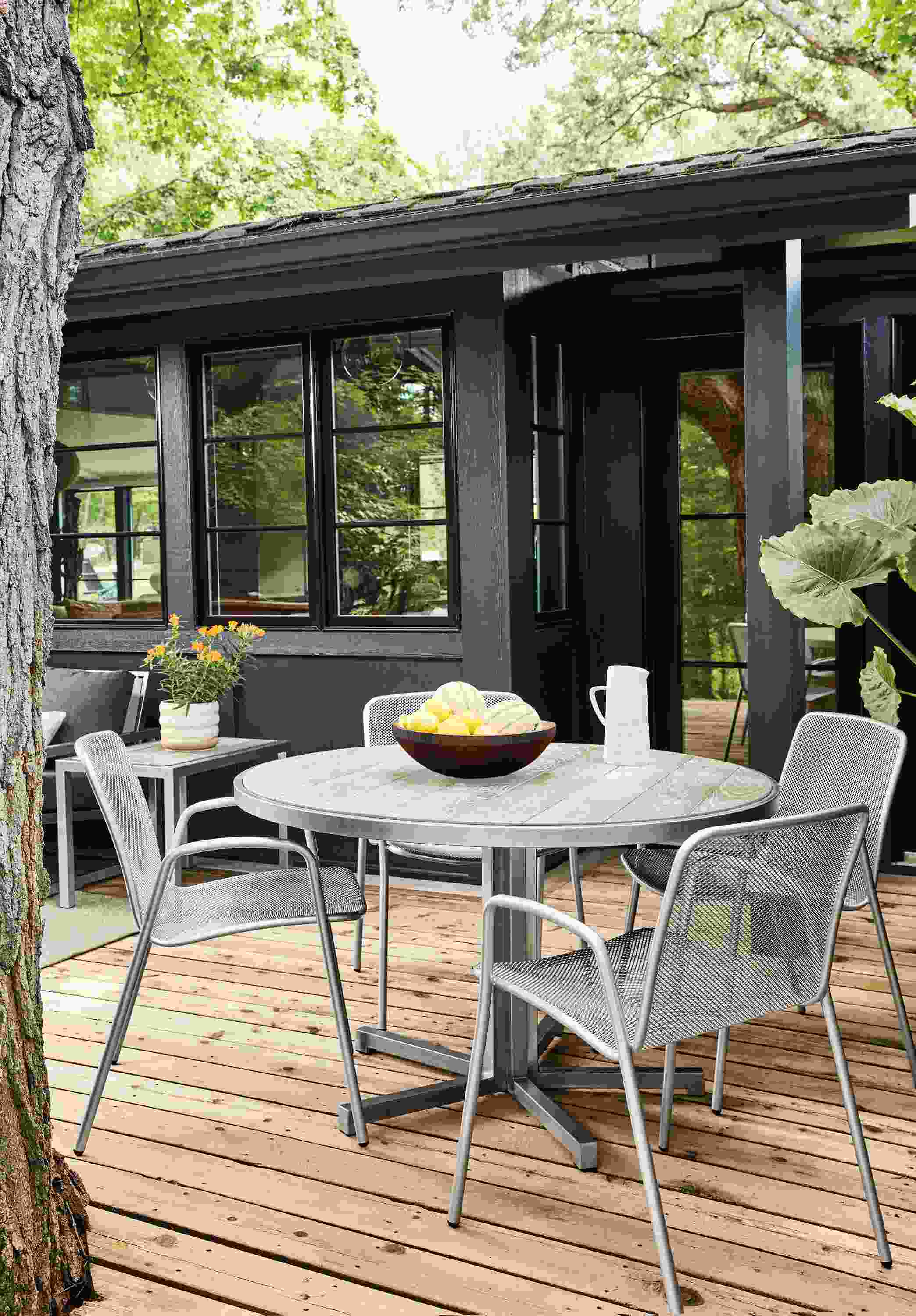 Montego 48-round outdoor dining table in stainless steel with aged thermally modified ash wood with Aruba chairs in silver.