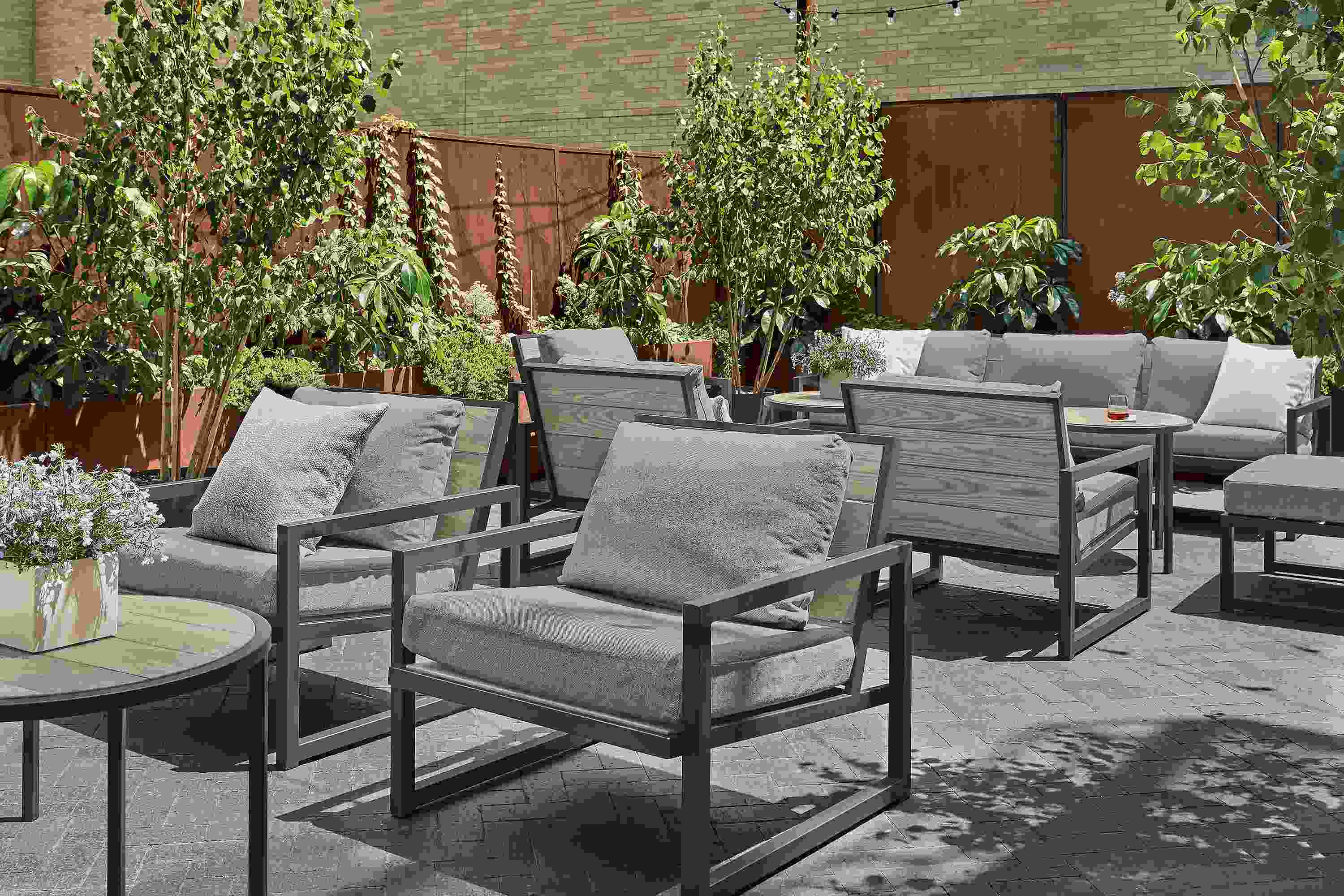 Outdoor lounge space with aged thermally modified oak montego chairs with mist steel cushions and Montego round side tables.