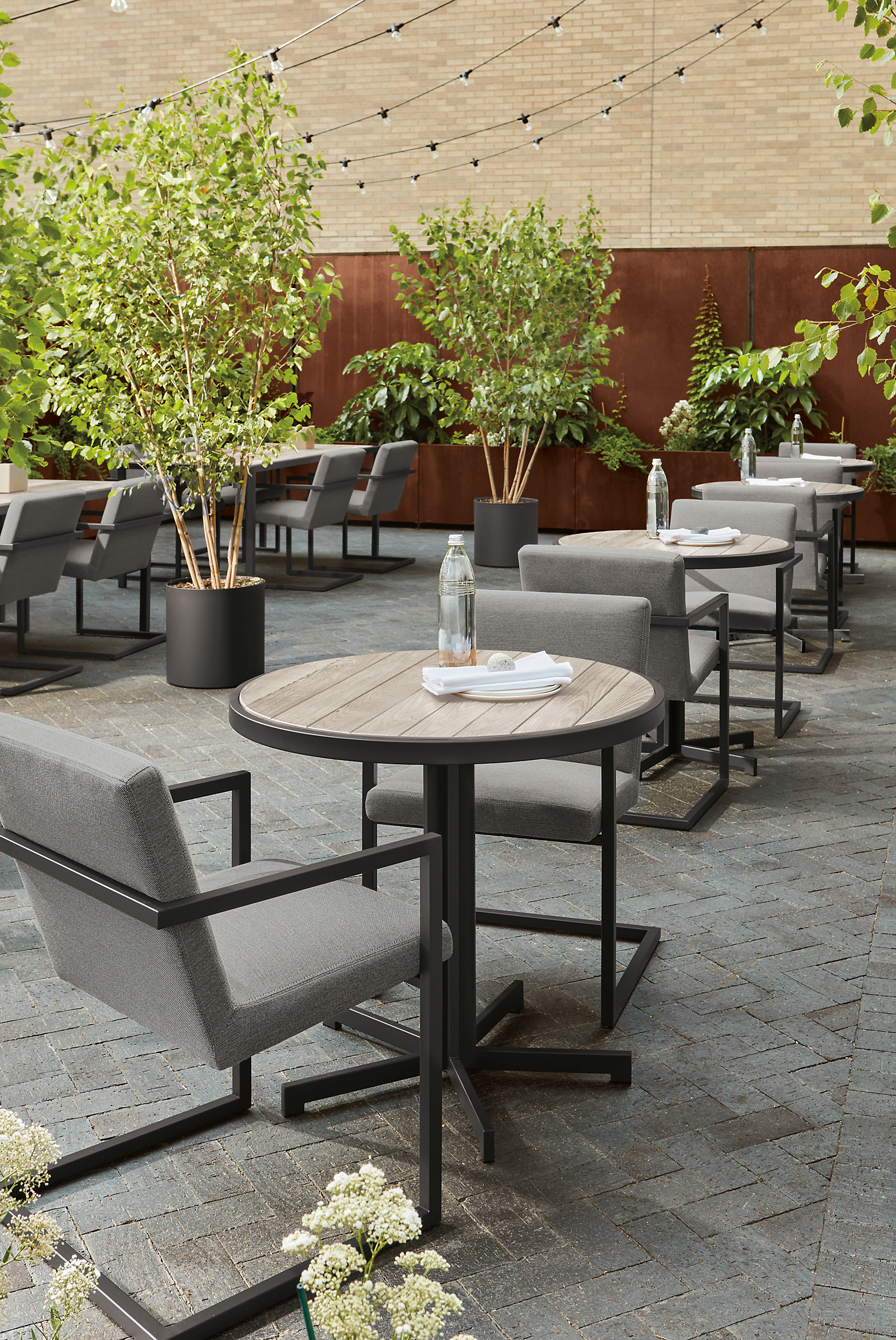outdoor commercial dining space with 4 aged thermally modified ash montego dining tables and finn arm chairs.