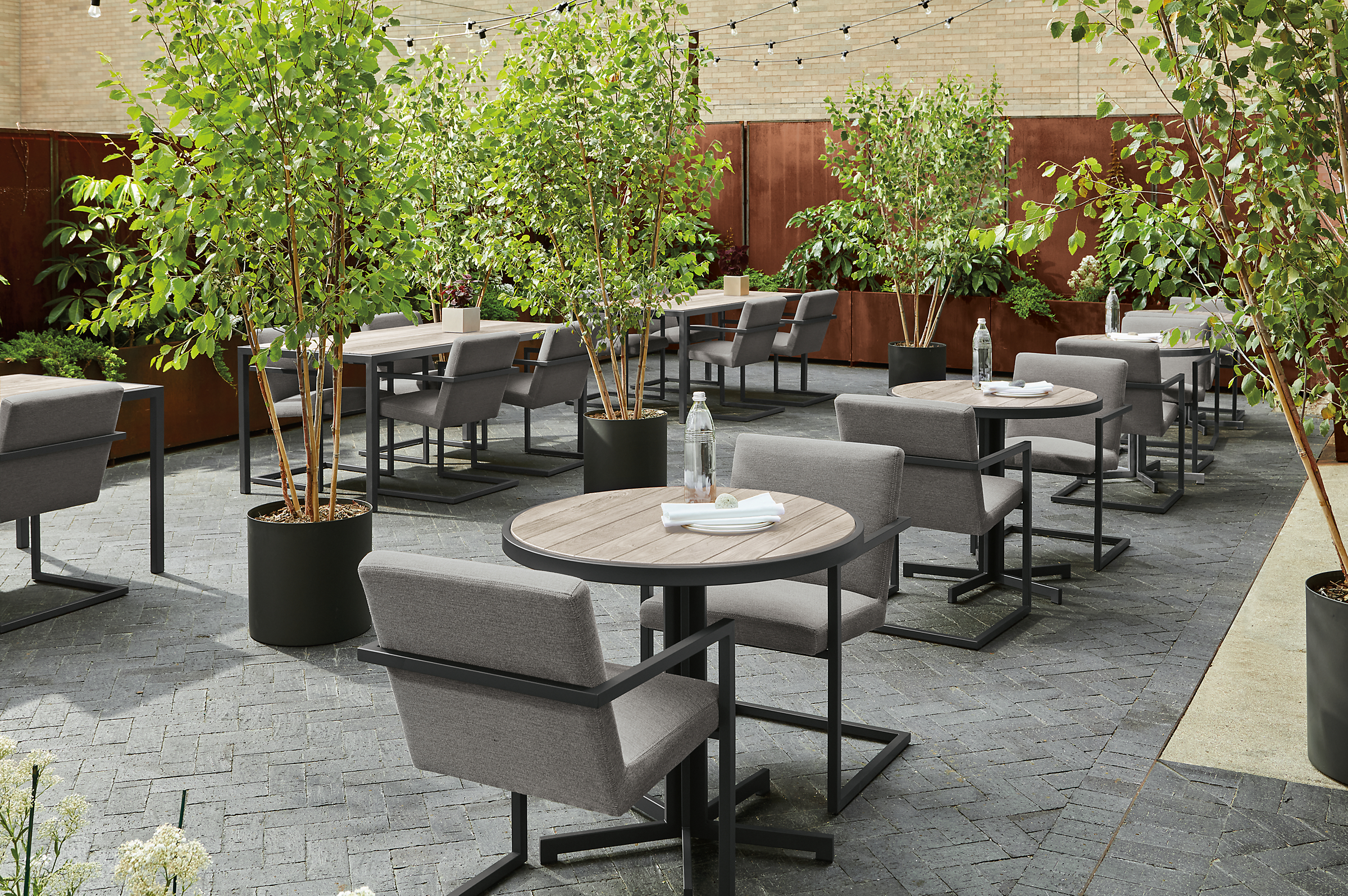outdoor commercial dining space with 4 round aged thermally modified ash montego dining tables and finn arm chairs.