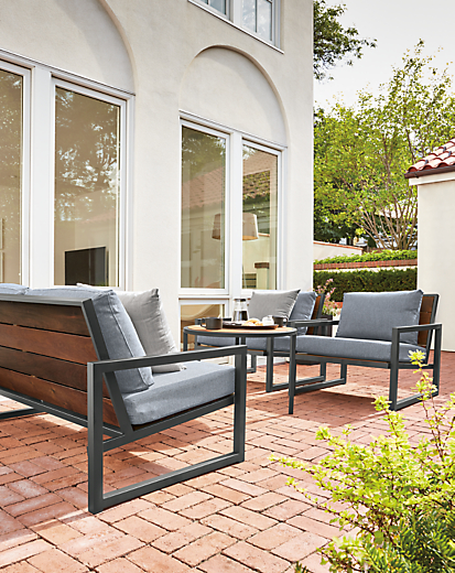 Outdoor patio setting with two Montego Lounge Chairs, Montego 57-wide Sofa and 27-round Coffee Table in Graphite. 
