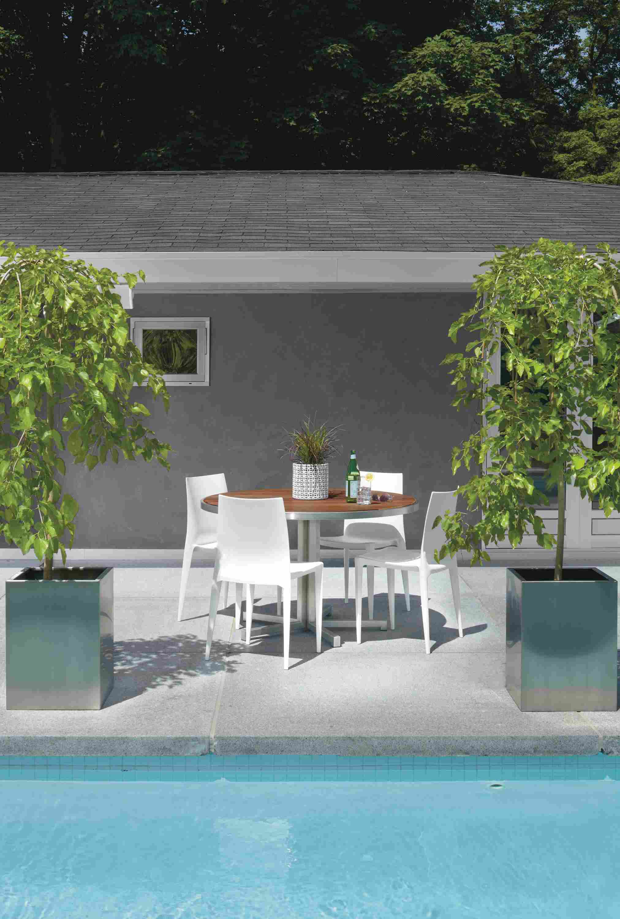 Outdoor pool setting with Montego 48-round Dining Table in Stainless Steel with four Bellini Chairs in White.