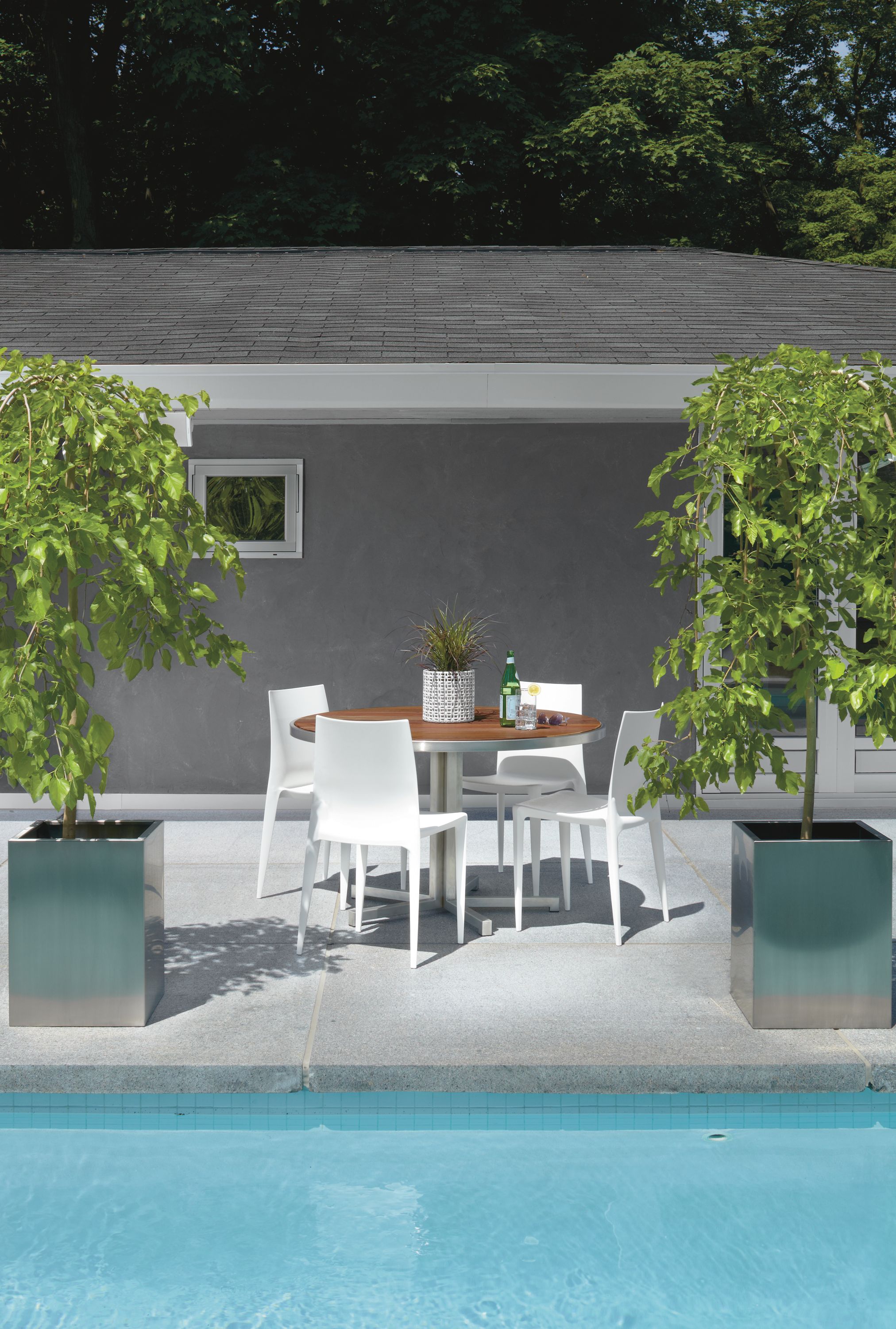 Outdoor pool setting with Montego 48-round Dining Table in Stainless Steel with four Bellini Chairs in White.