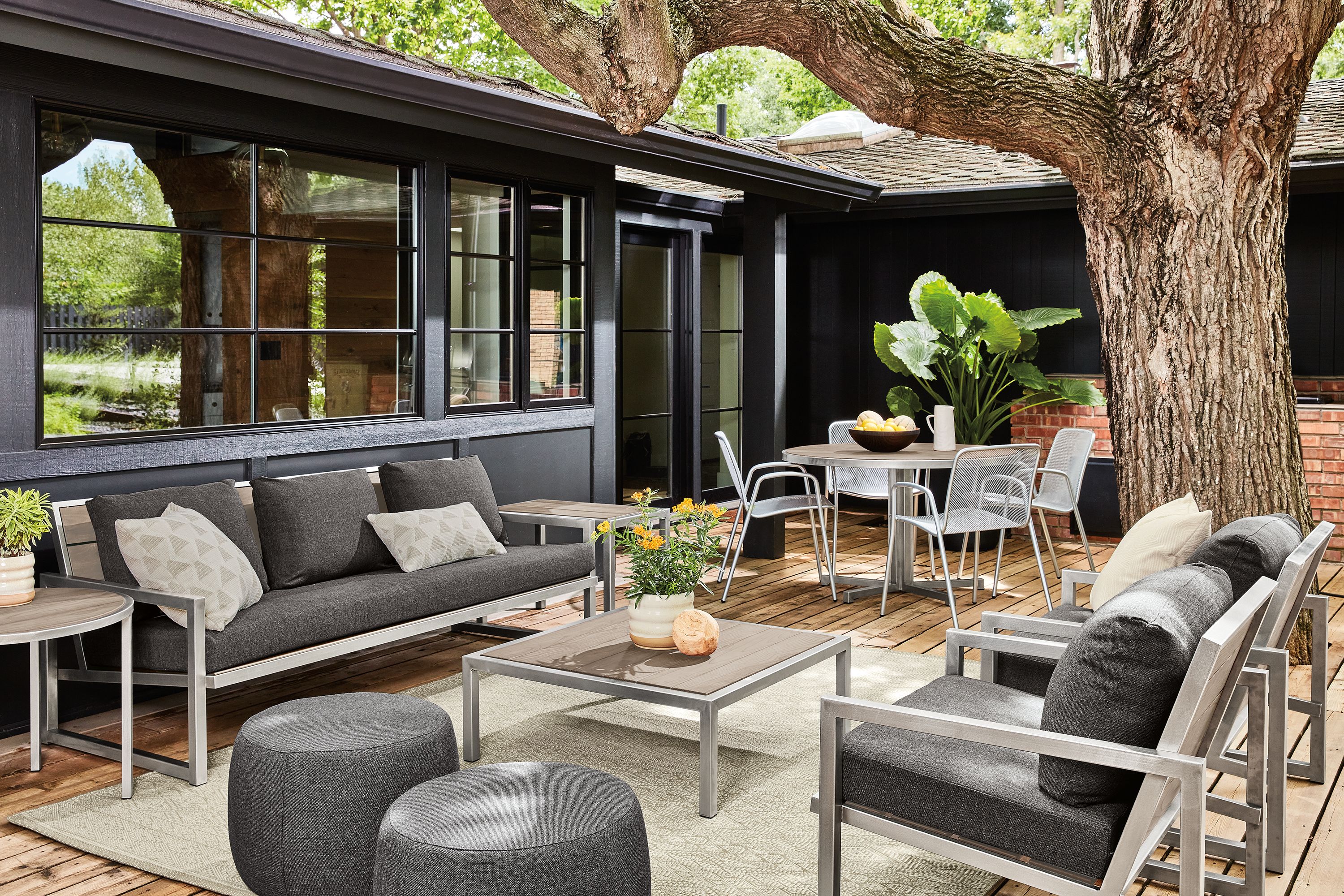 Montego sofa, chairs with Mist charcoal cushions, coffee table and end tables in stainless steel with aged thermally modified oak wood.