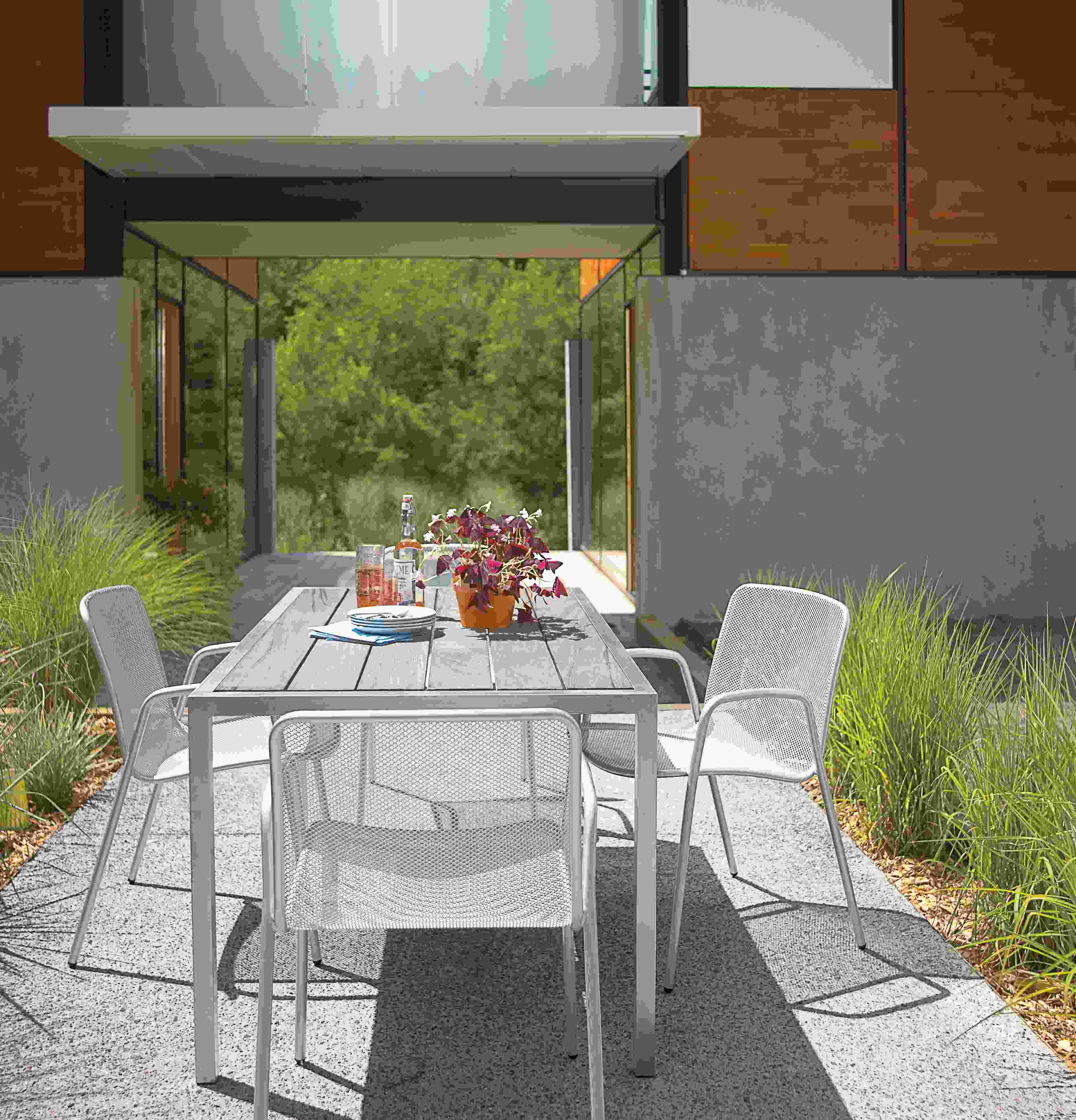 Patio with Montego 60-wide table in aged thermally modified ash and stainless steel and 4 Aruba chairs in silver.