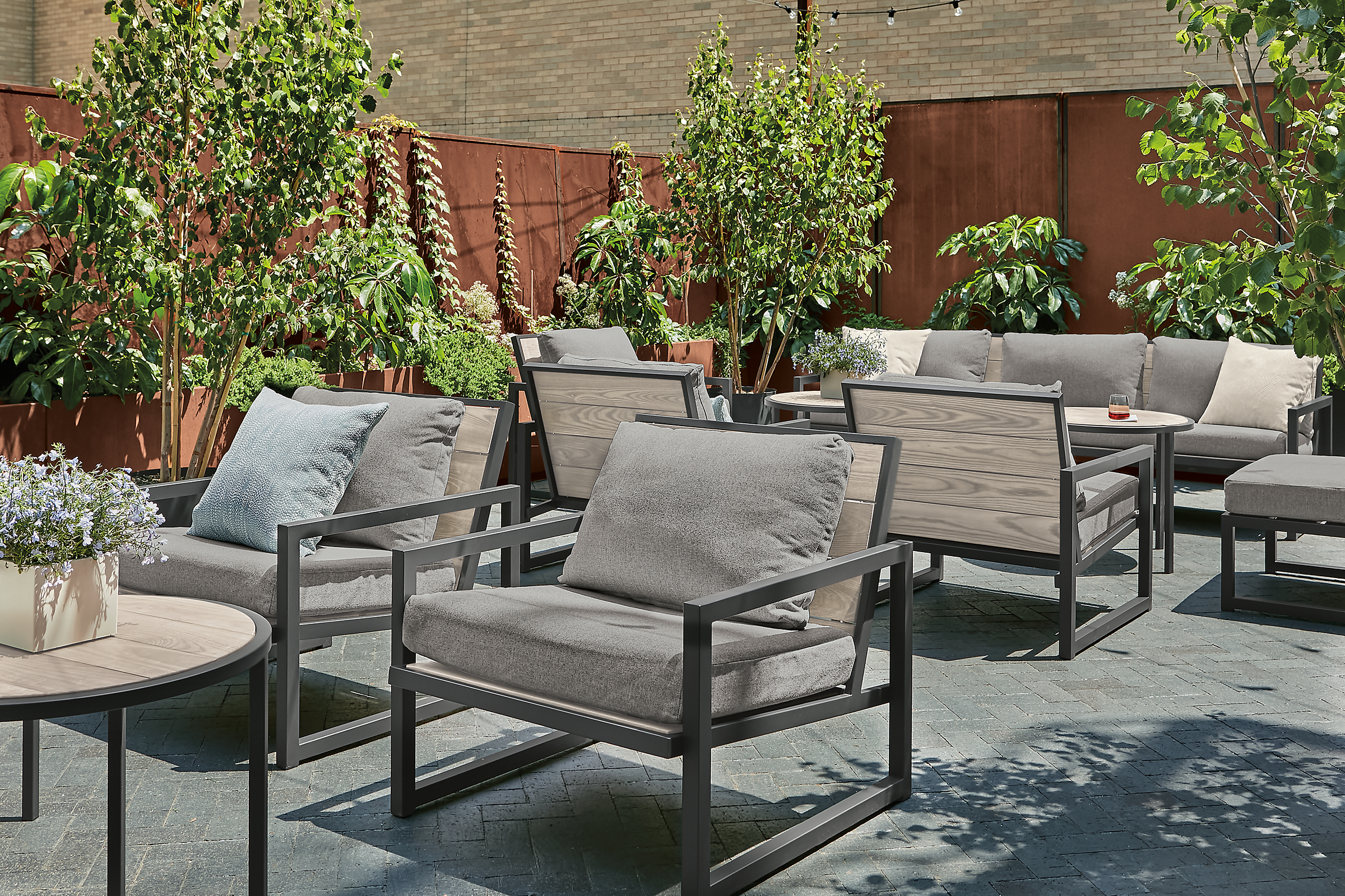 Outdoor lounge space with aged thermally modified ash montego chairs and sofas with cushions.