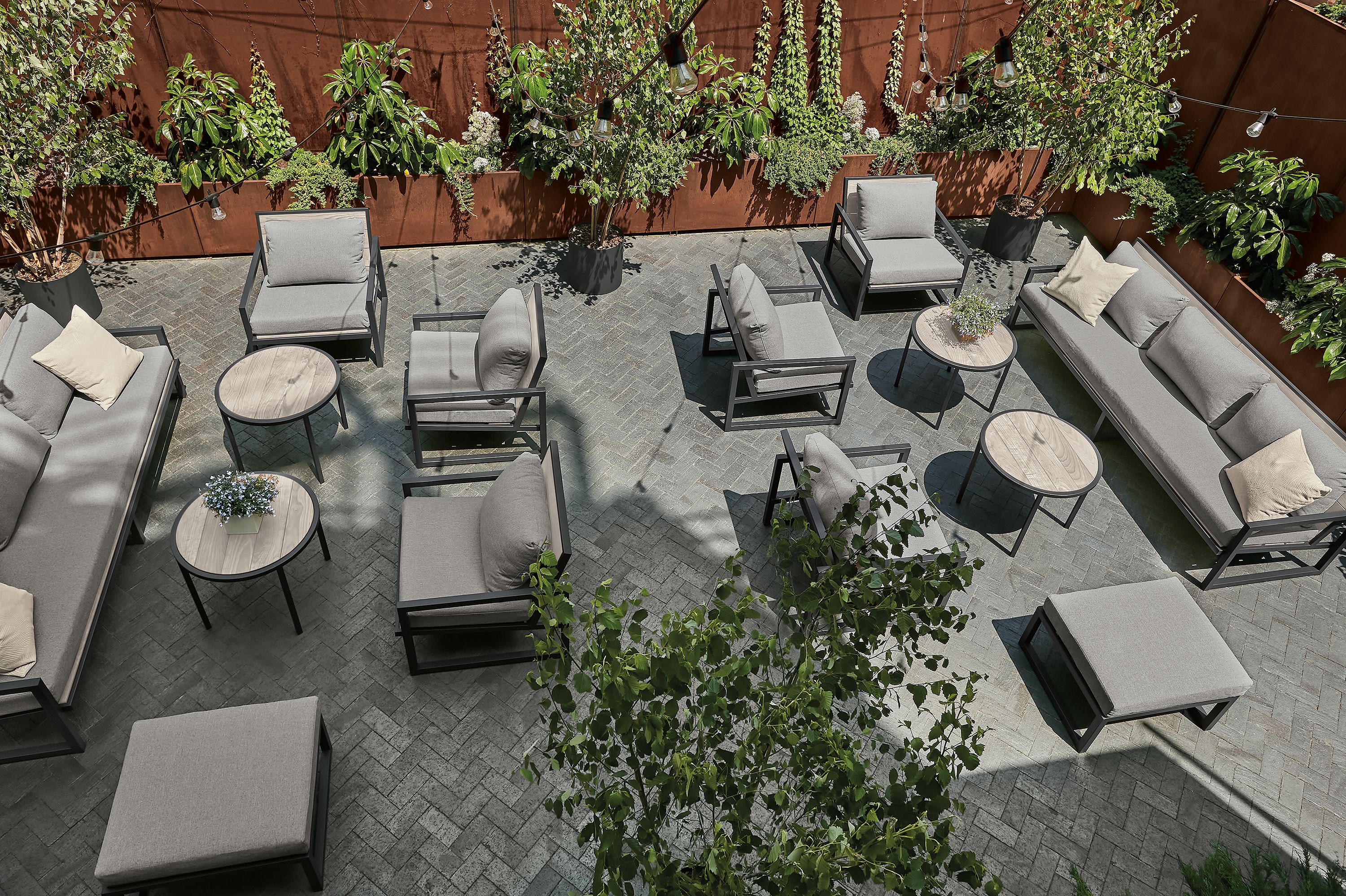 top-down view of outdoor lounge space with aged thermally modified ash montego side tables, chairs and sofas with cushions.