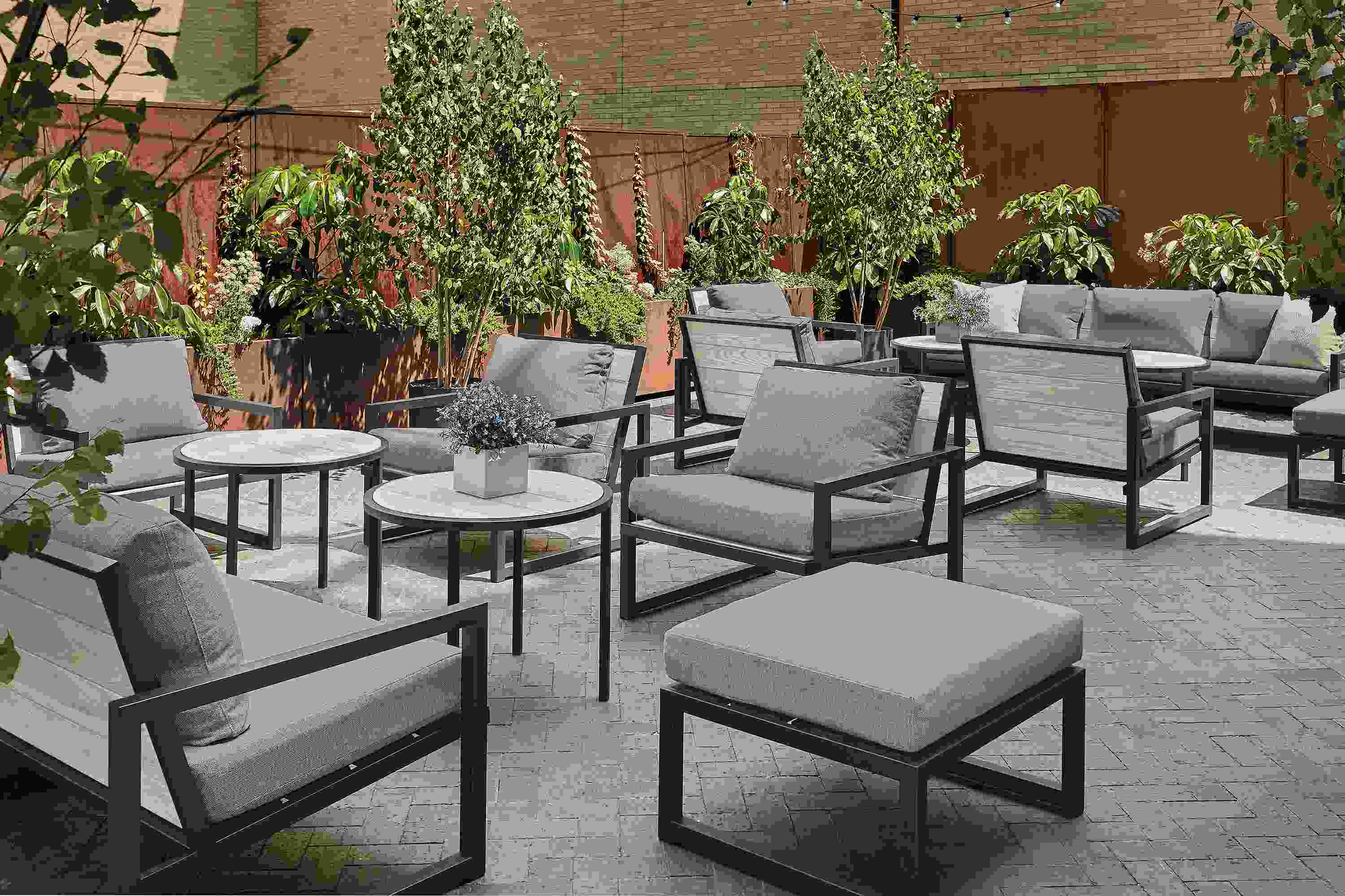 Outdoor lounge space with aged thermally modified ash montego chairs with cushions and montego round side tables.