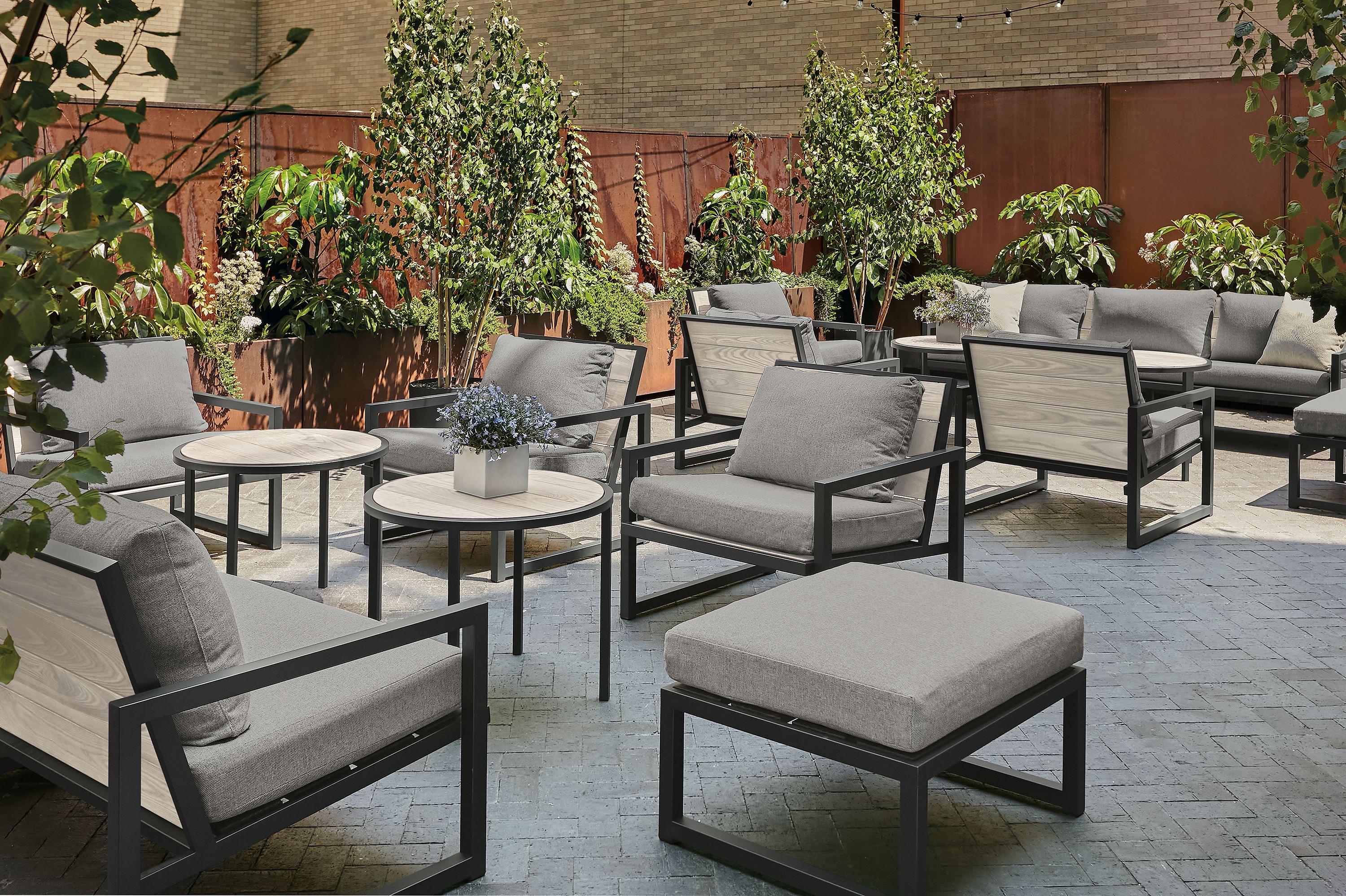 Outdoor lounge space with aged thermally modified ash montego chairs with cushions and montego round side tables.