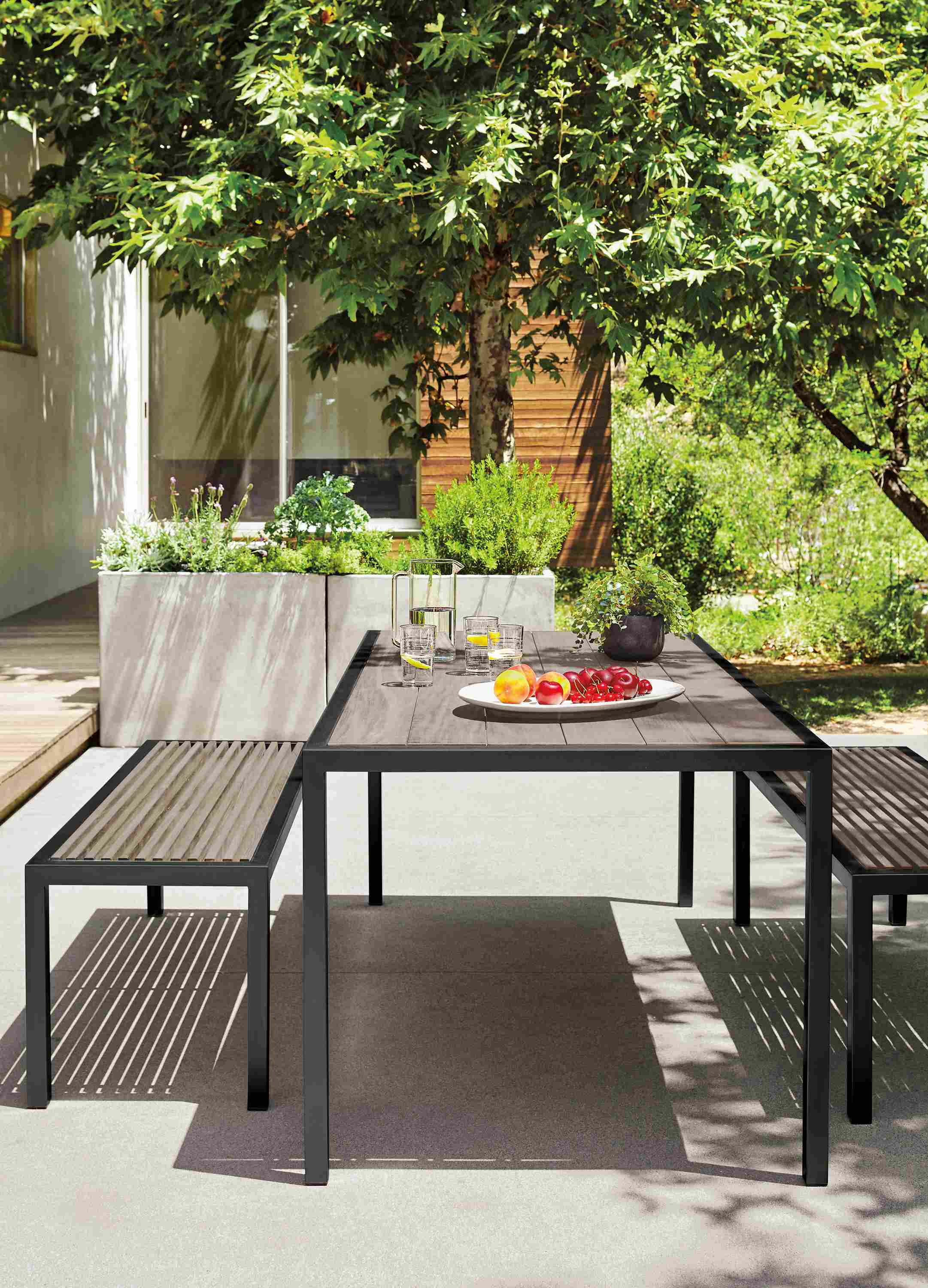 Patio with montego table and 2 montego benches in aged thermally modified oak and six bellini chairs in black.