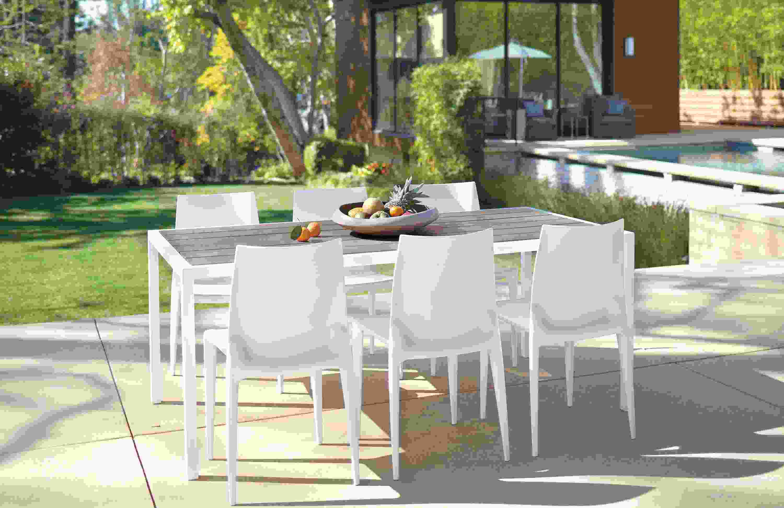 Dining patio near a pool with Montego table in aged thermally modified oak and white and 6 Bellini chairs in white.