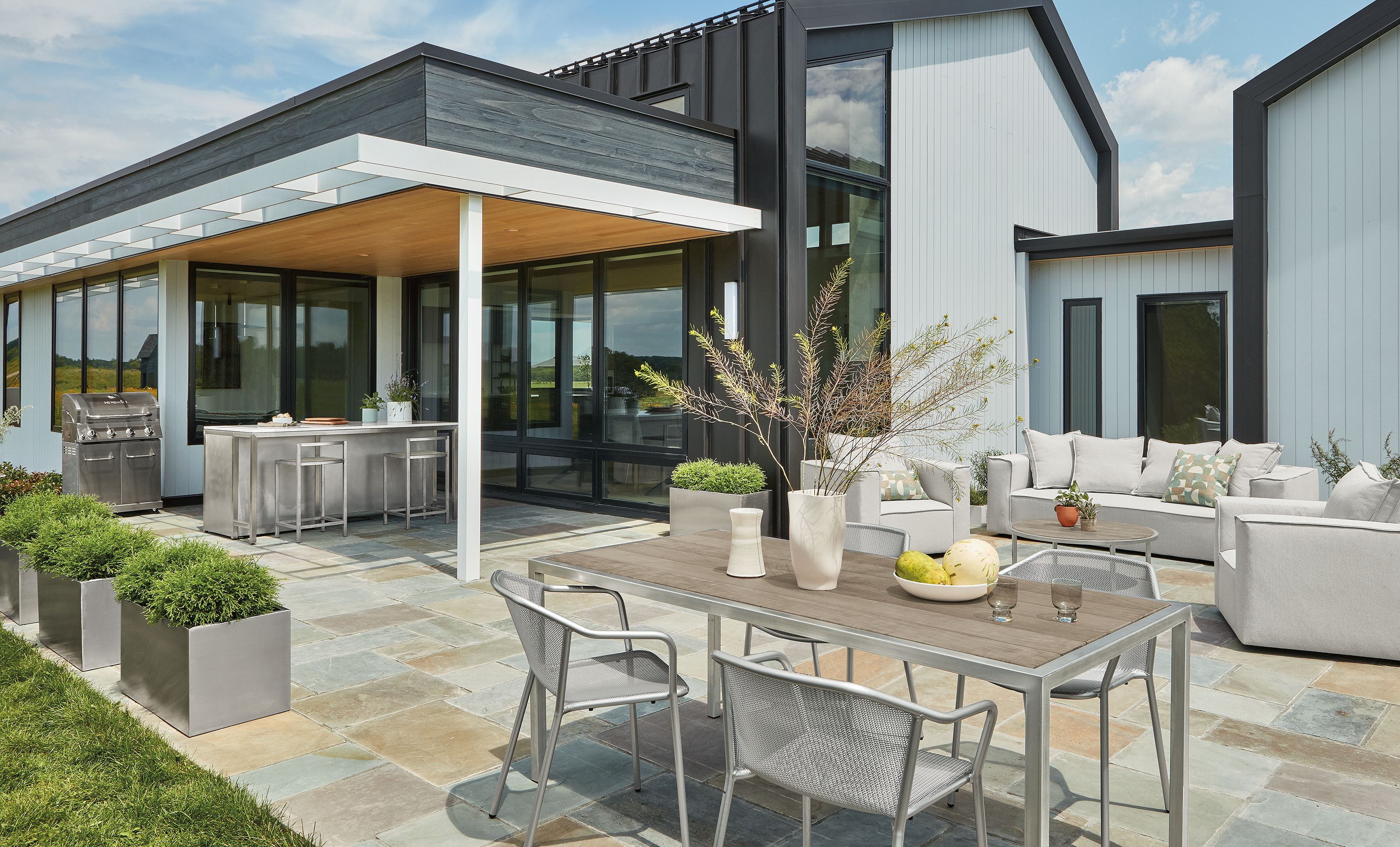 Patio with montego table in stainless with aged thermally modified oak and 4 theo chairs in silver.