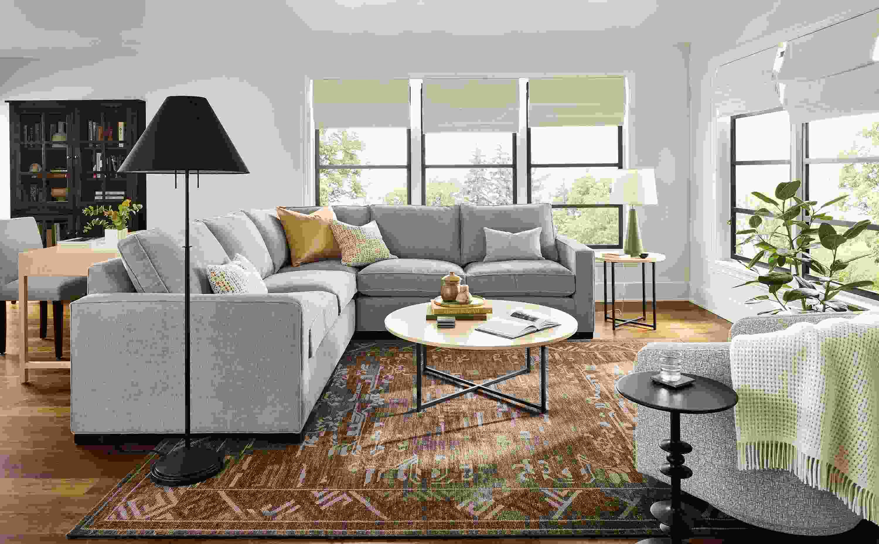 Living room with morrison 3-piece sectional sofa in hawkins cement and classic round table in natural steel with ecru quartz top.