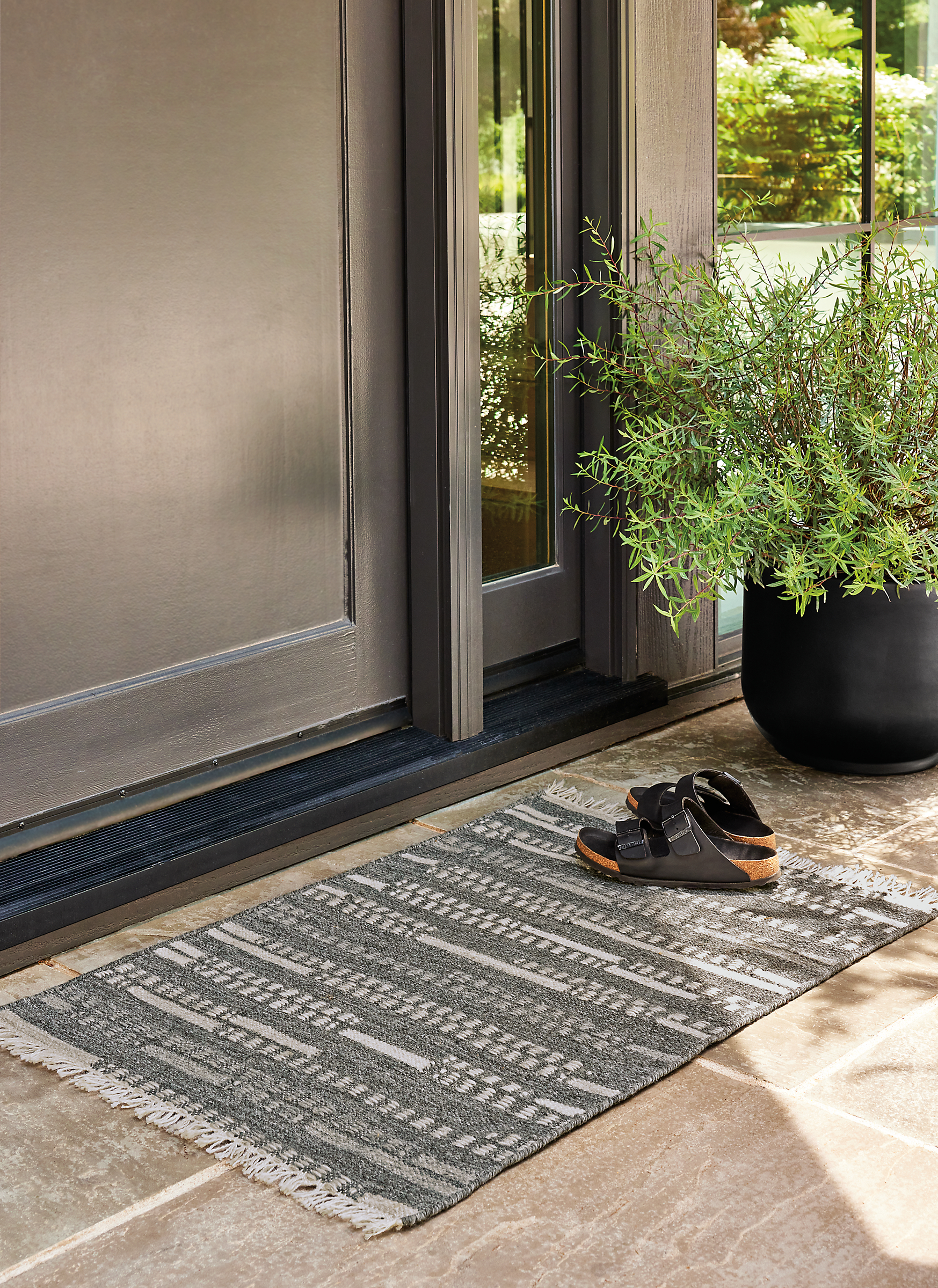 Outdoor space with small morse rug and cassius planter.