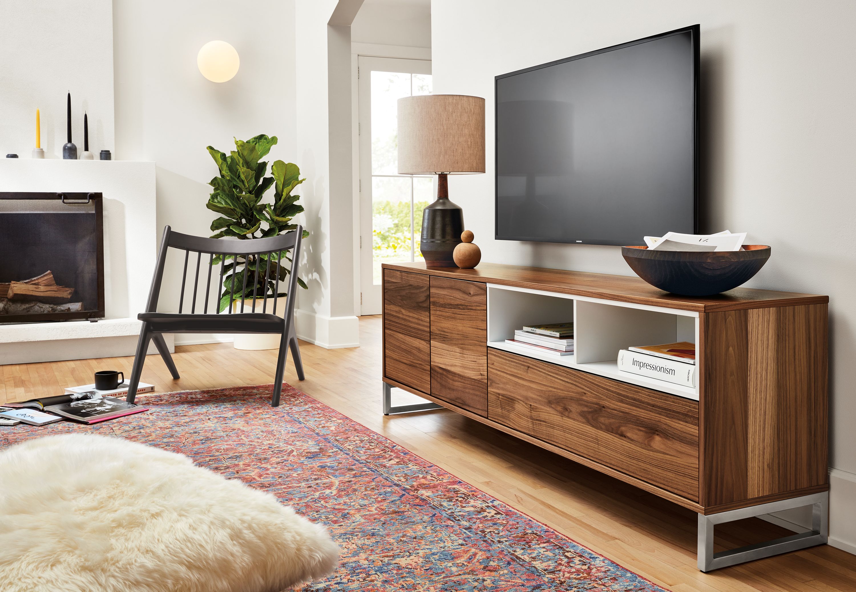 Living room setting with a Mosby storage cabinet and an Oskar Armless Lounge Chair in Charcoal on a Cassia Rug in Pink.