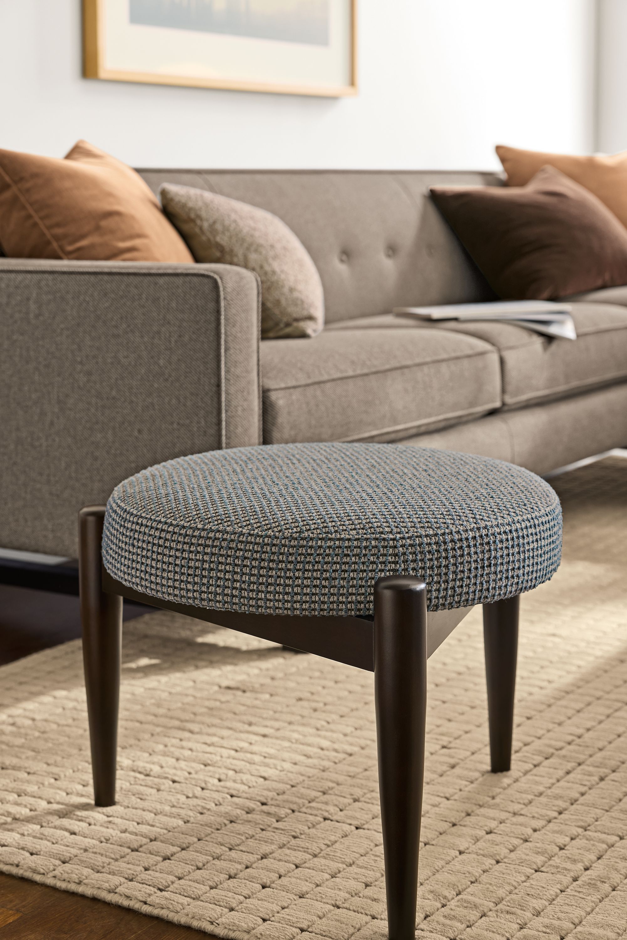 Living room with Murphy 25-diameter stool in Dorsa charcoal, Safira rug in Ecru and Andre sofa in Derry Charcoal.