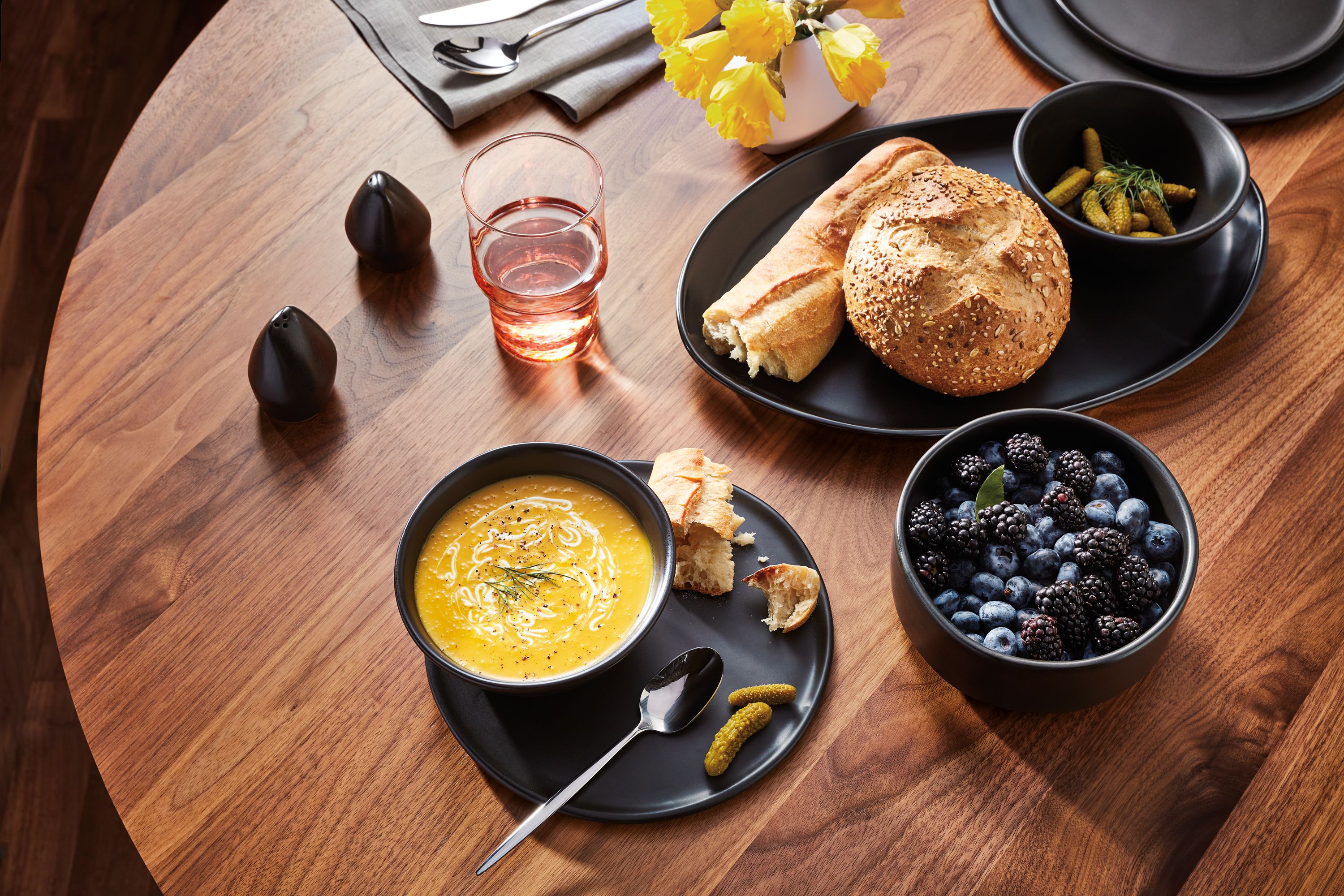 Table setting with Nadia servingware on an Aria table in Walnut.