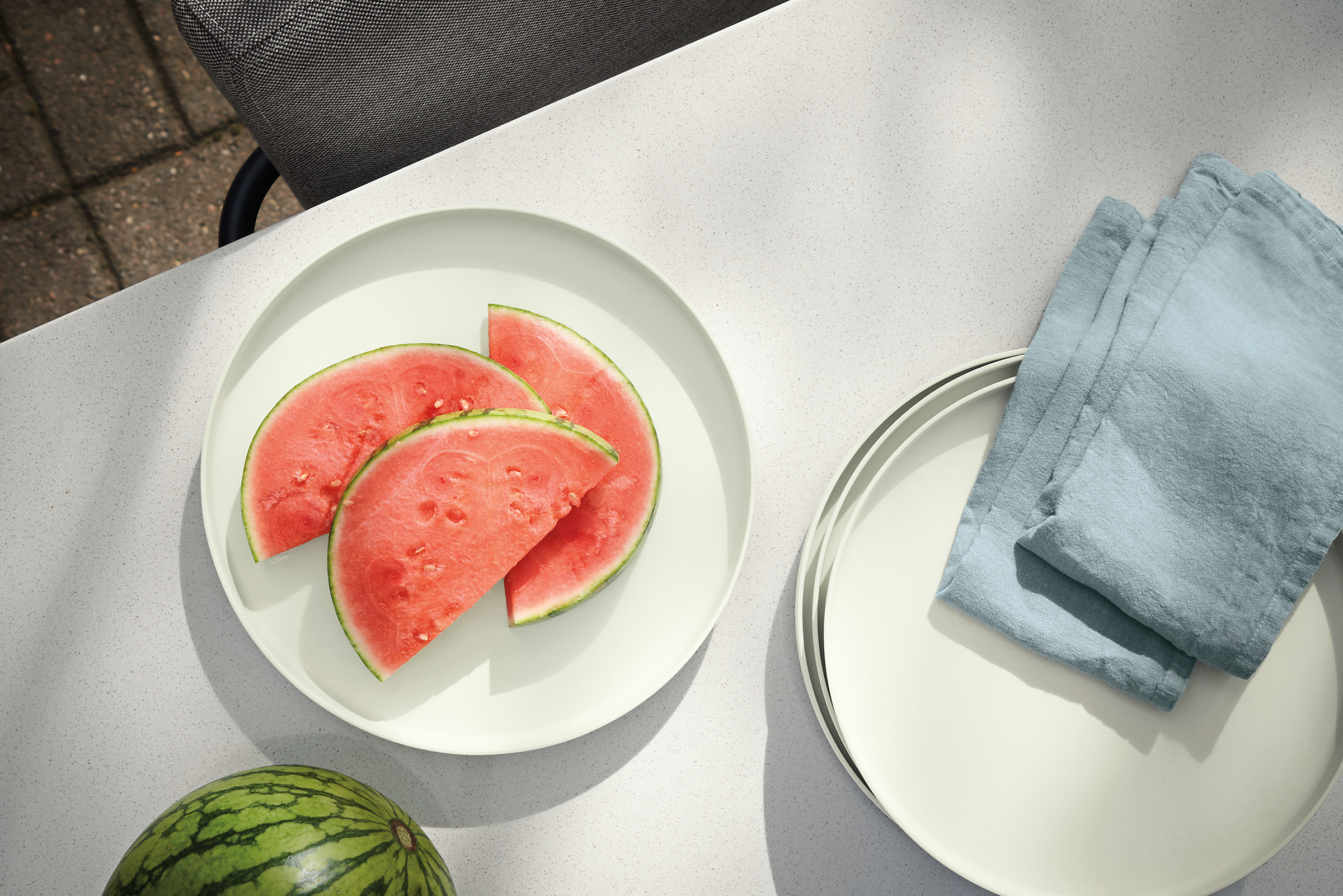 outdoor table with namu dinner plates in off-white with watermelon and maria linen napkins.