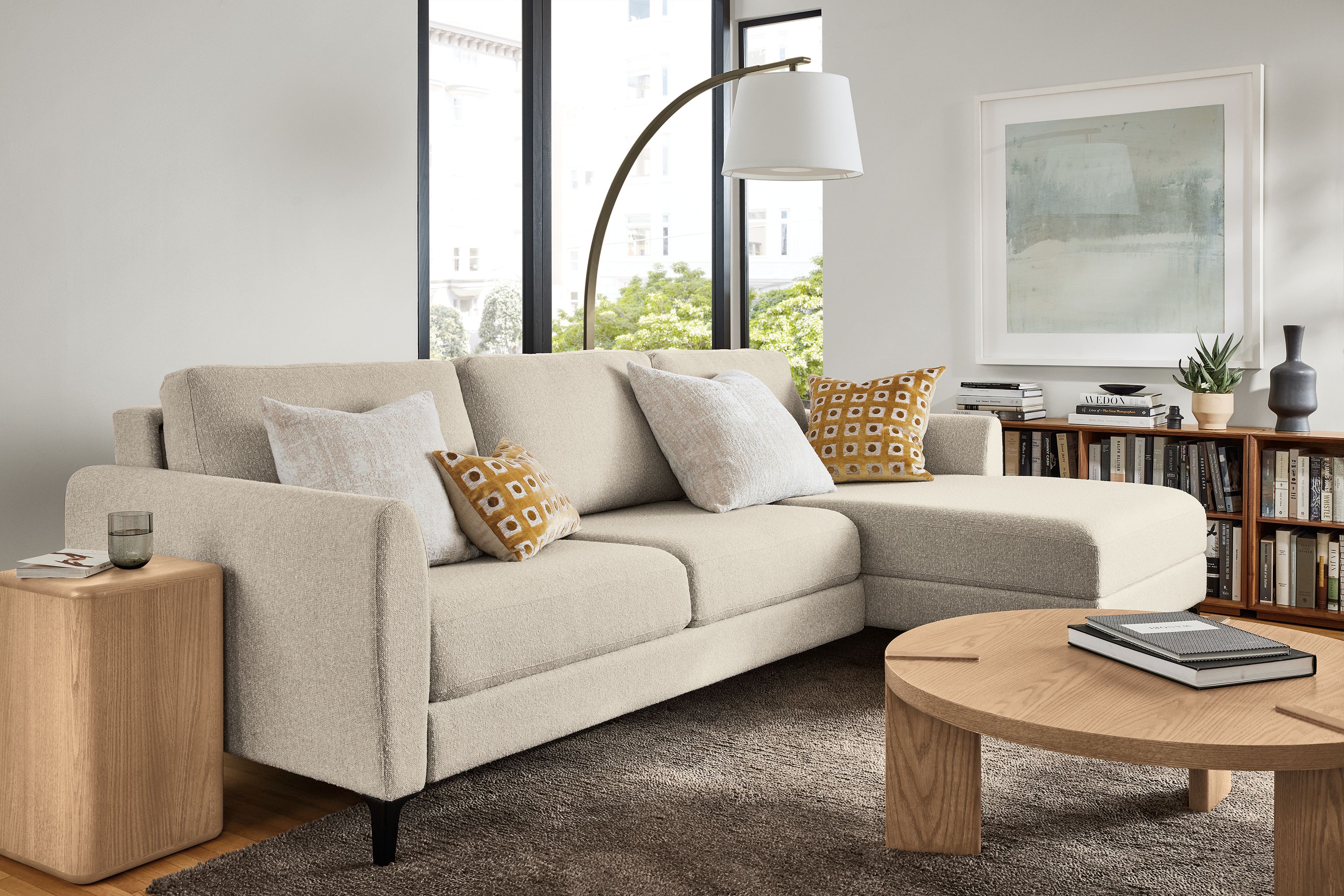 Living room with Natalia 102-wide sleeper sofa in Conley Natural and Hanover round coffee table in rye on red oak.