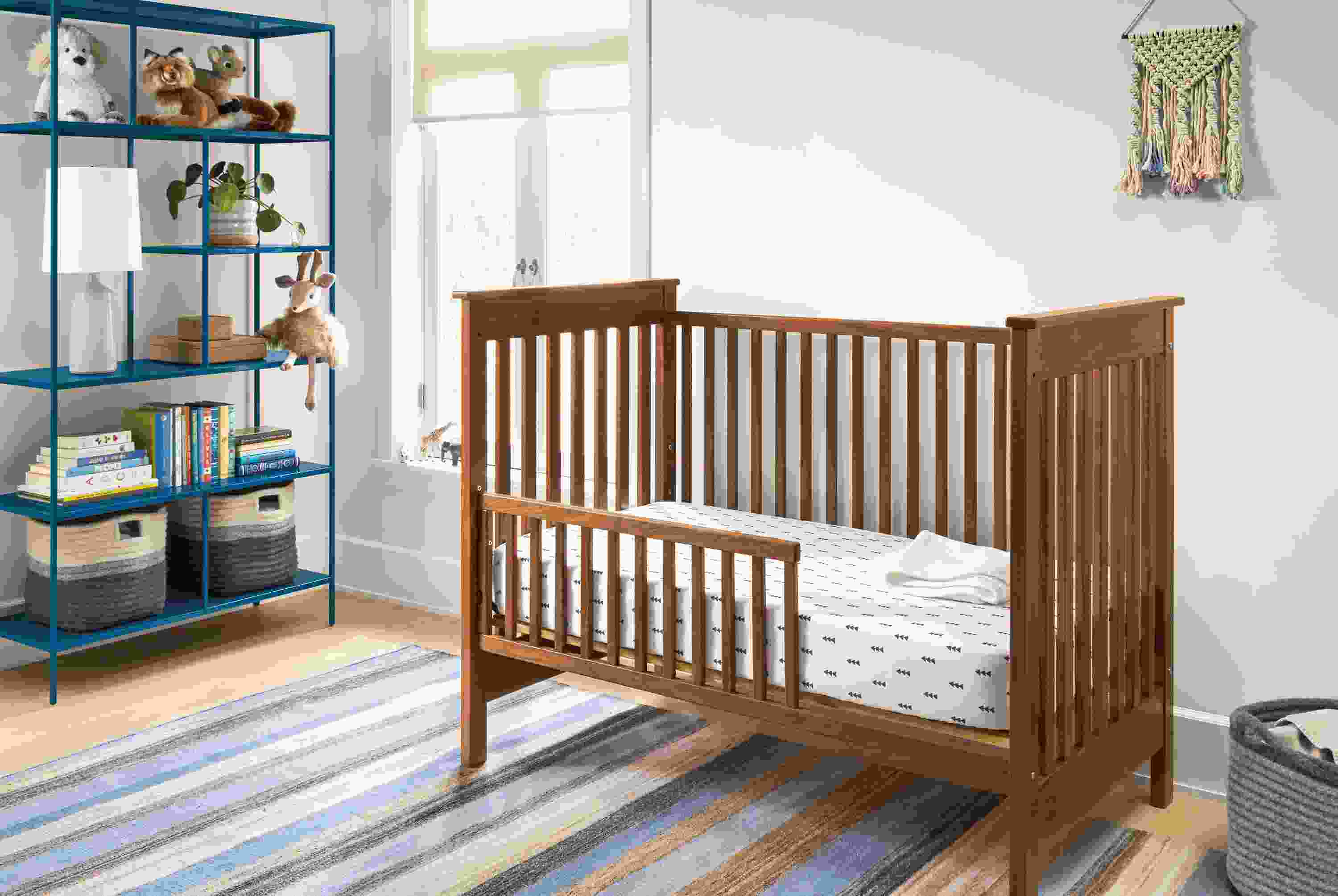 Detail of Nest crib in walnut in kids room with blue bookcase.