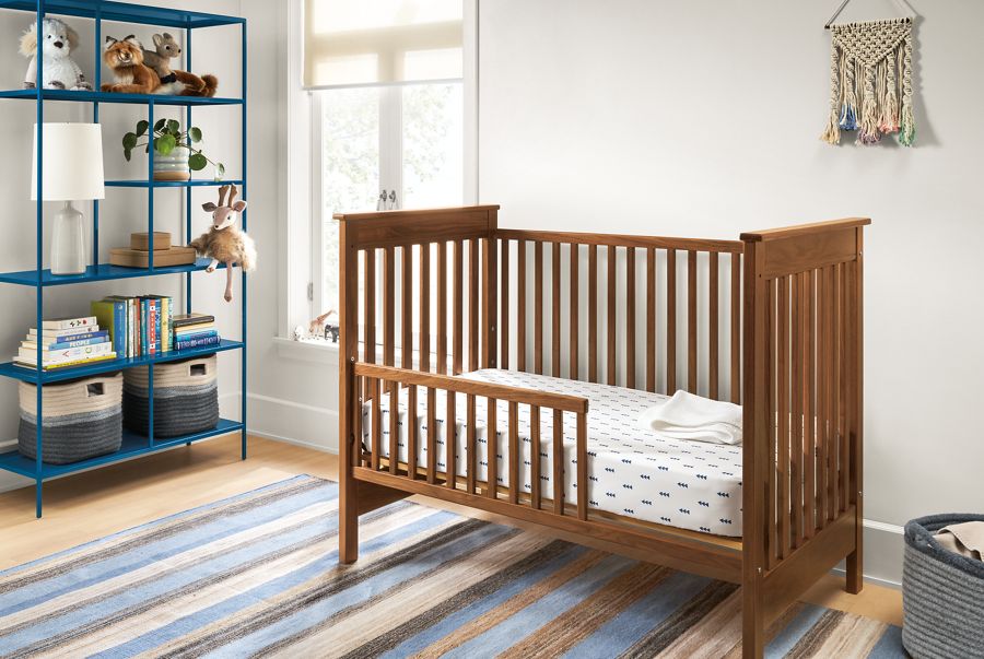 Detail of Nest crib in walnut in kids room with blue bookcase.