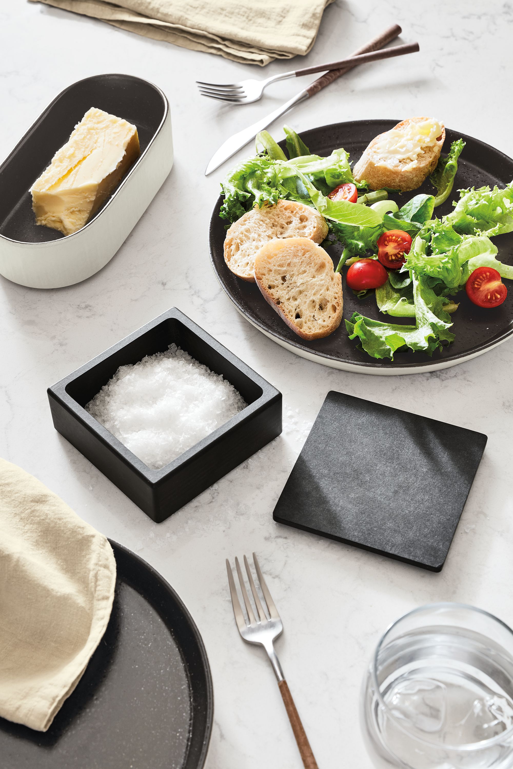 tabletop with nikko salt cellar, notos plate, notos oval tray, mito flatware.