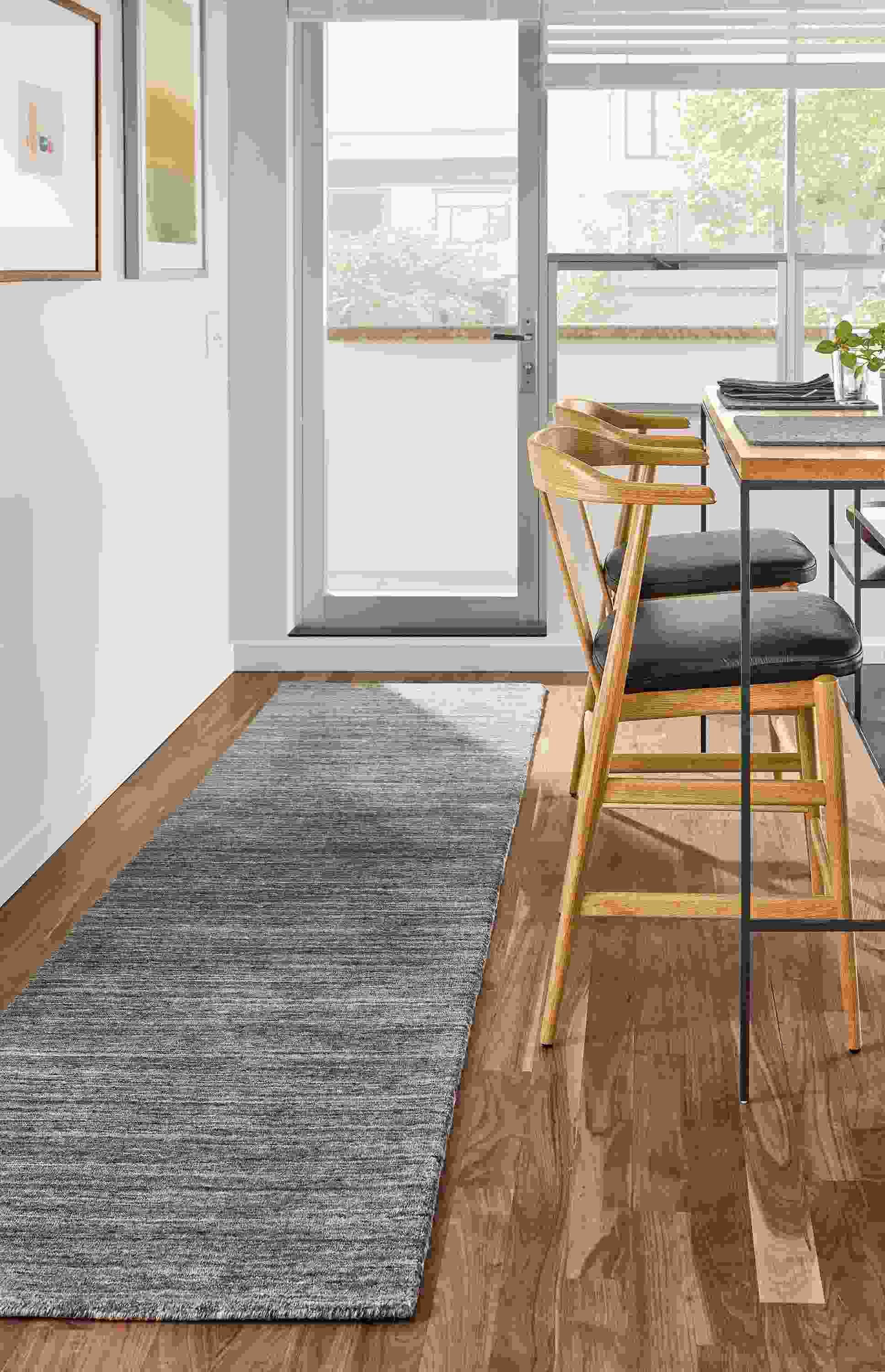 Kitchen room setting with two Evan counter stools in Pistel Leather and a Bowen Counter Table and a Nomad rug in Charcoal.