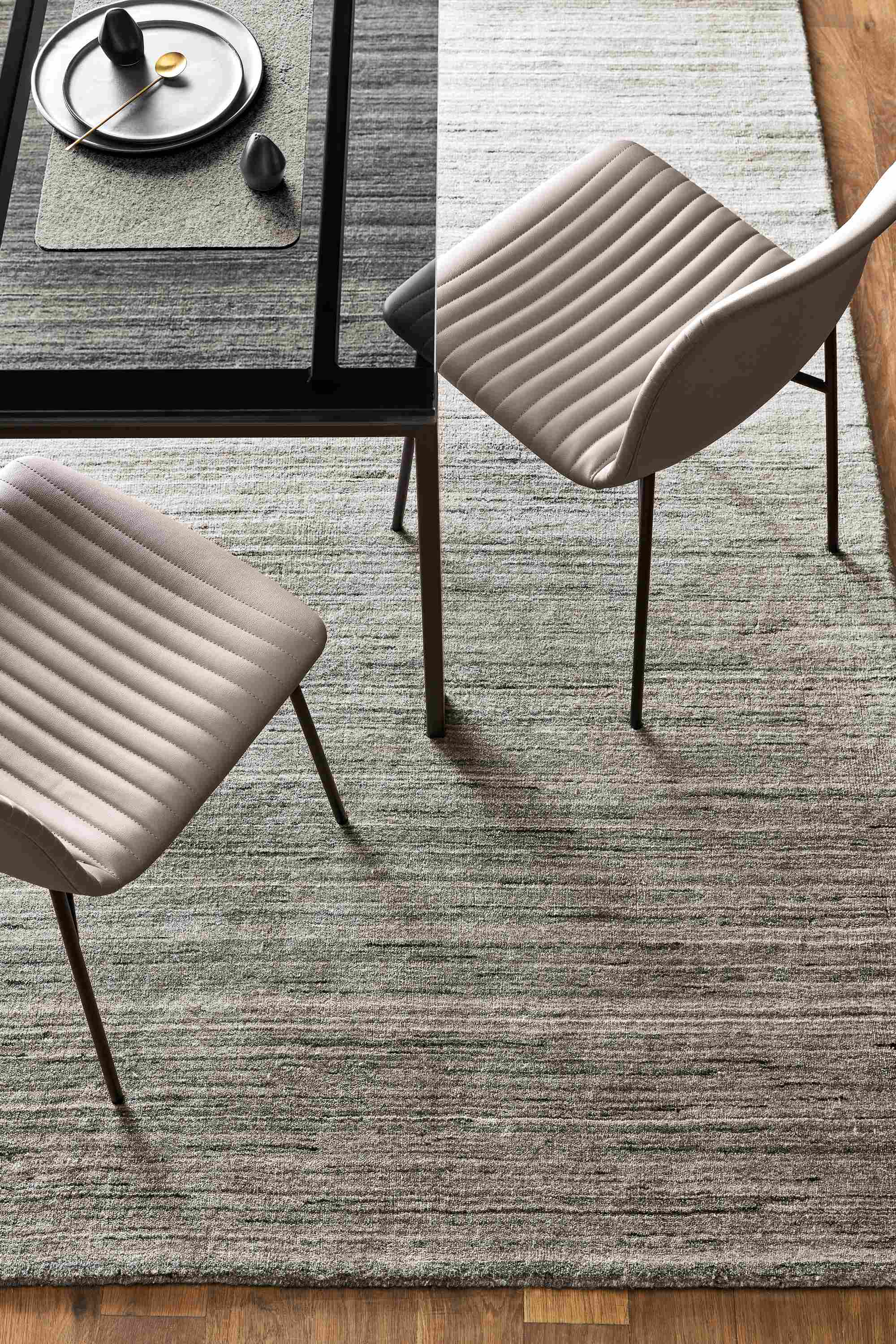 Overhead view of Rand table in Natural Steel and two Cato side chairs in Sarno leather, with a Nomad rug in Charcoal.
