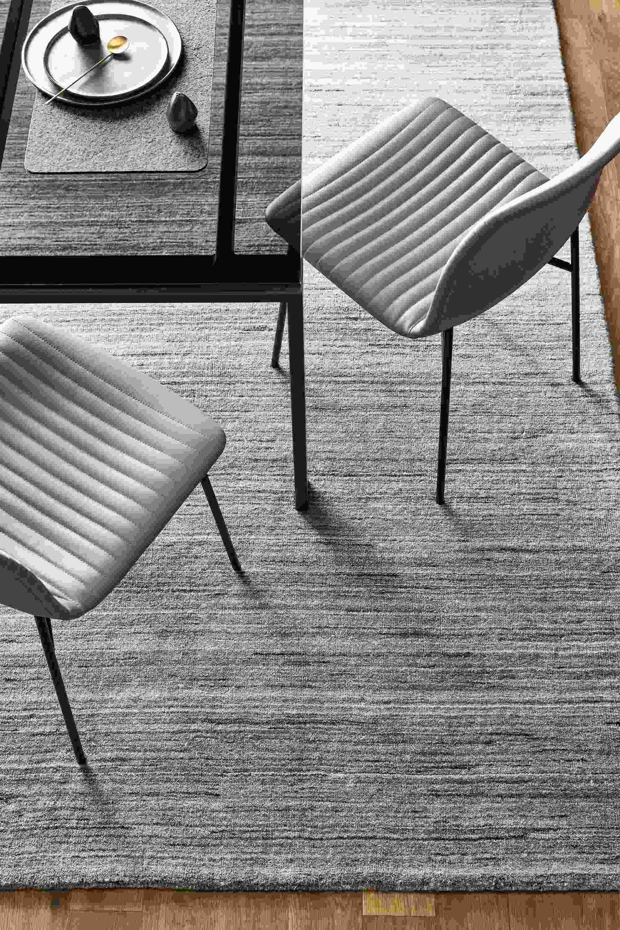 Overhead view of Rand table in Natural Steel and two Cato side chairs in Sarno leather, with a Nomad rug in Charcoal.