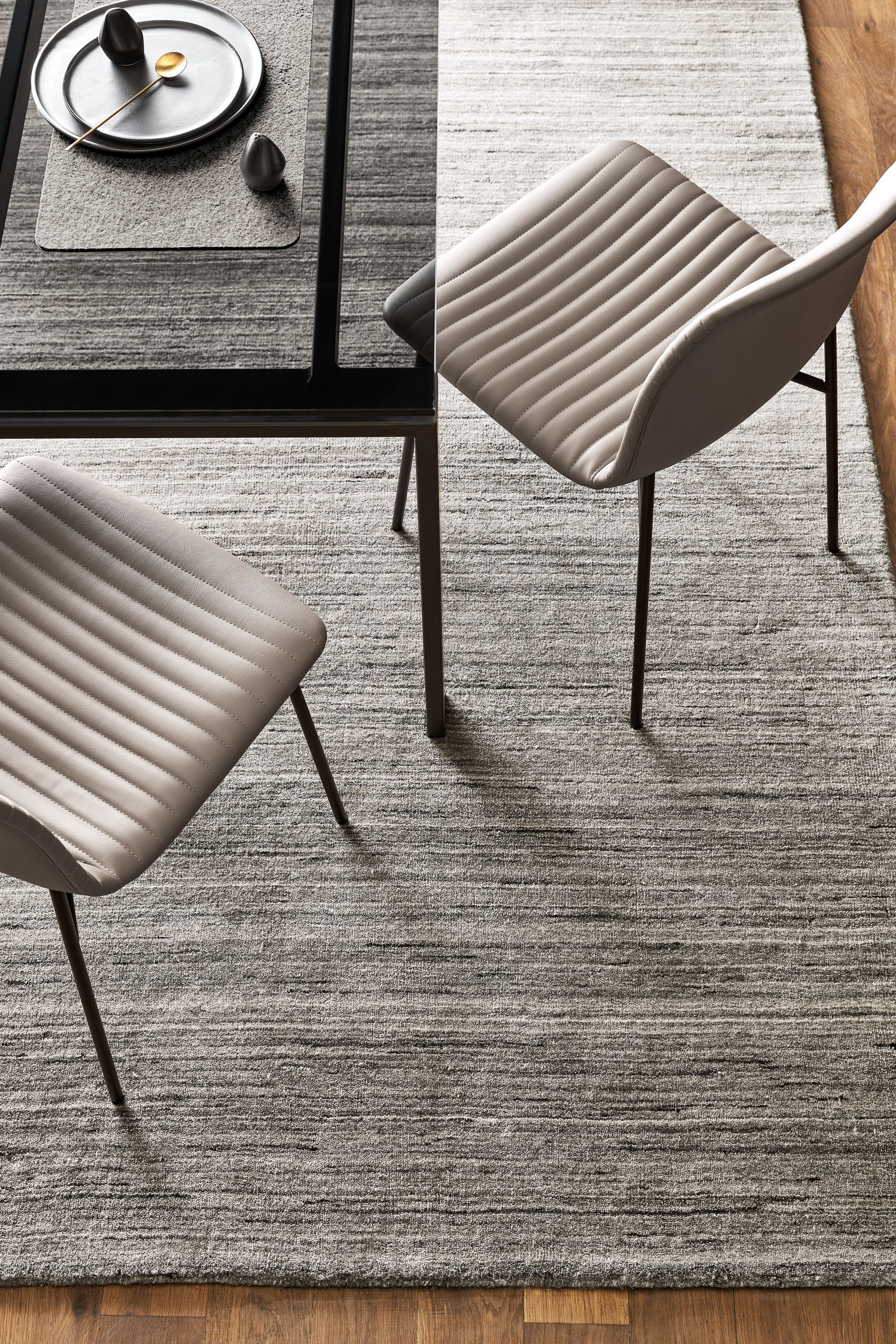 Overhead view of Rand table in Natural Steel and two Cato side chairs in synthetic leather, with a Nomad rug in Charcoal.