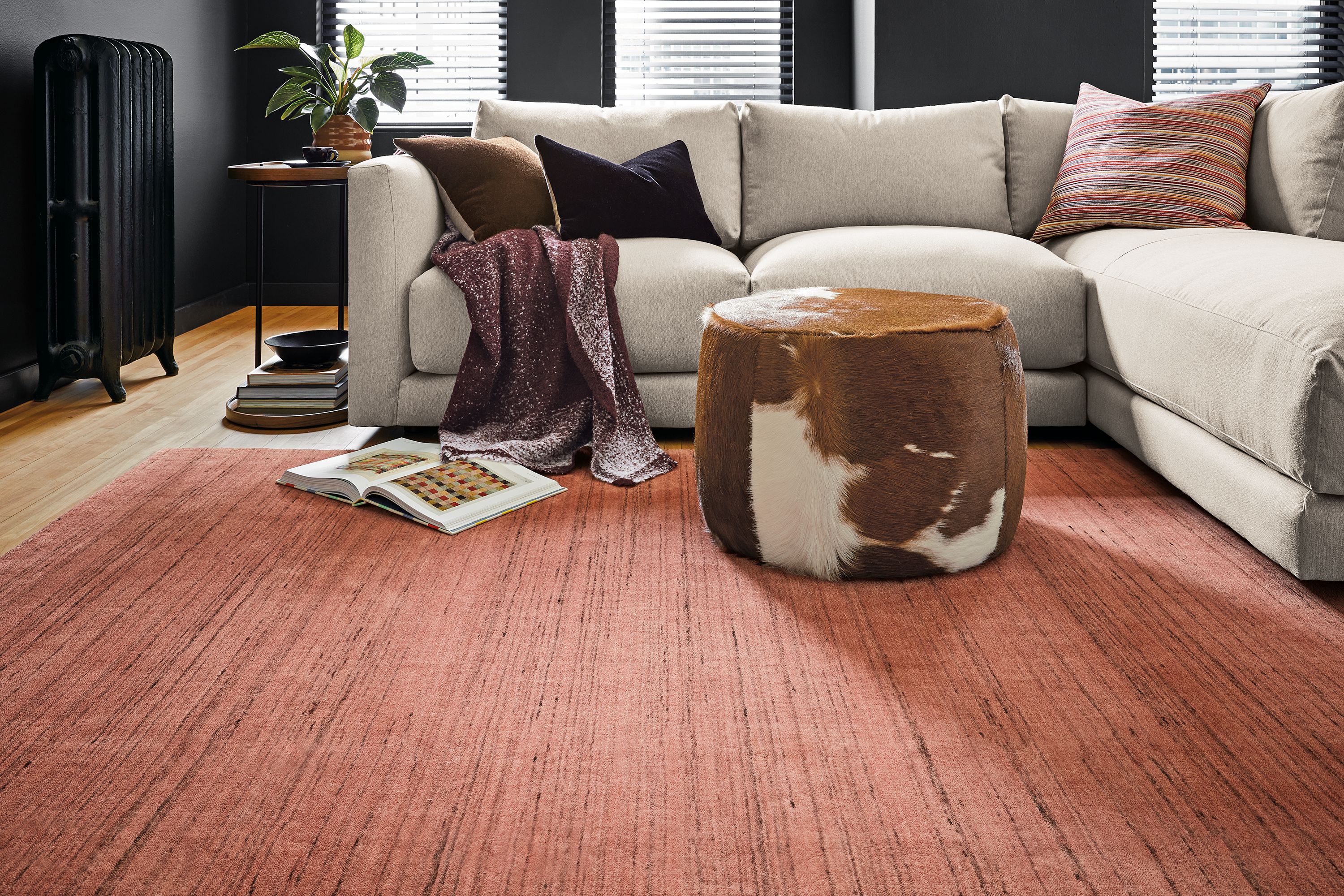 Room setting with a Clemens sofa and chaise, Perimeter C-table in Walnut and Nomad rug in Terracotta.