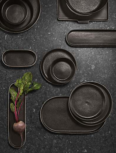 overhead view of notos dishware in black stacked on tabletop.