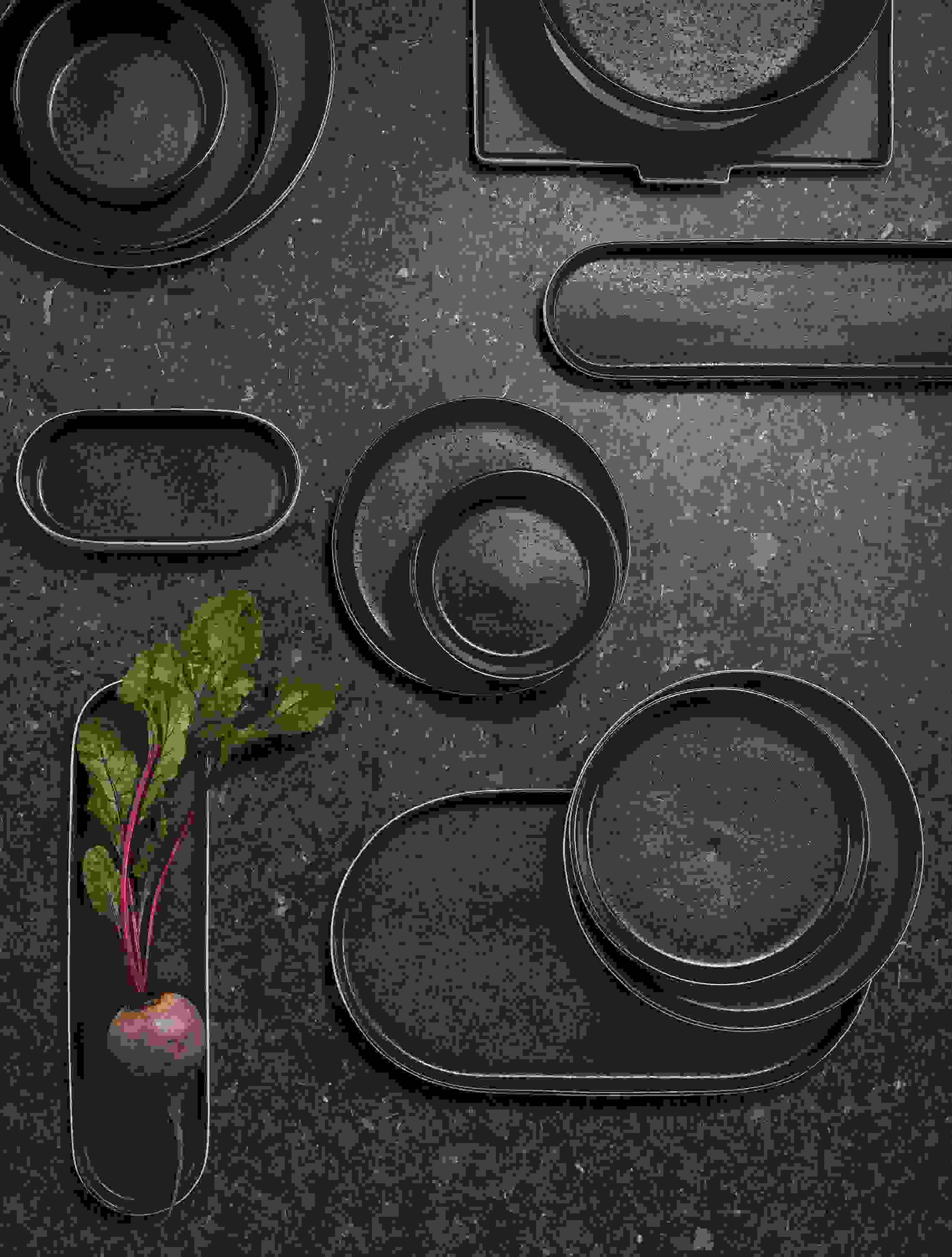 overhead view of notos dishware in black stacked on tabletop.