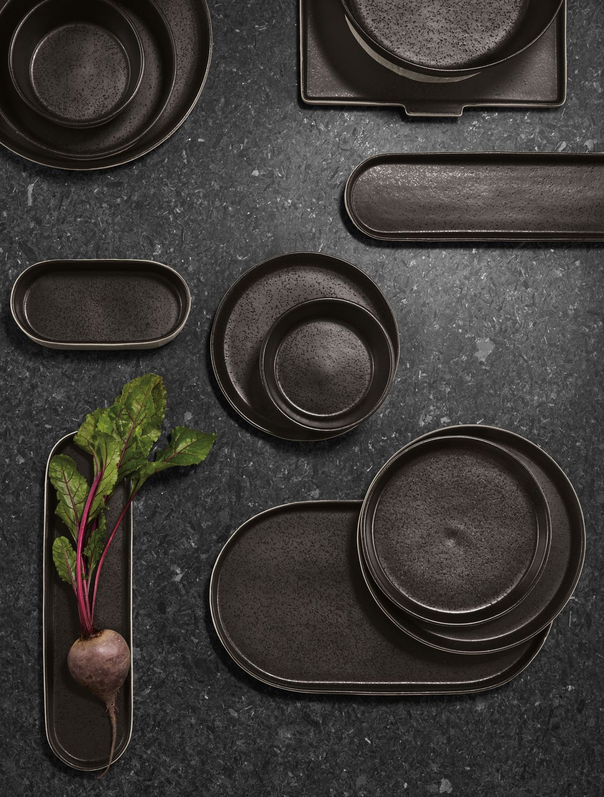 overhead view of notos dishware in black stacked on tabletop.