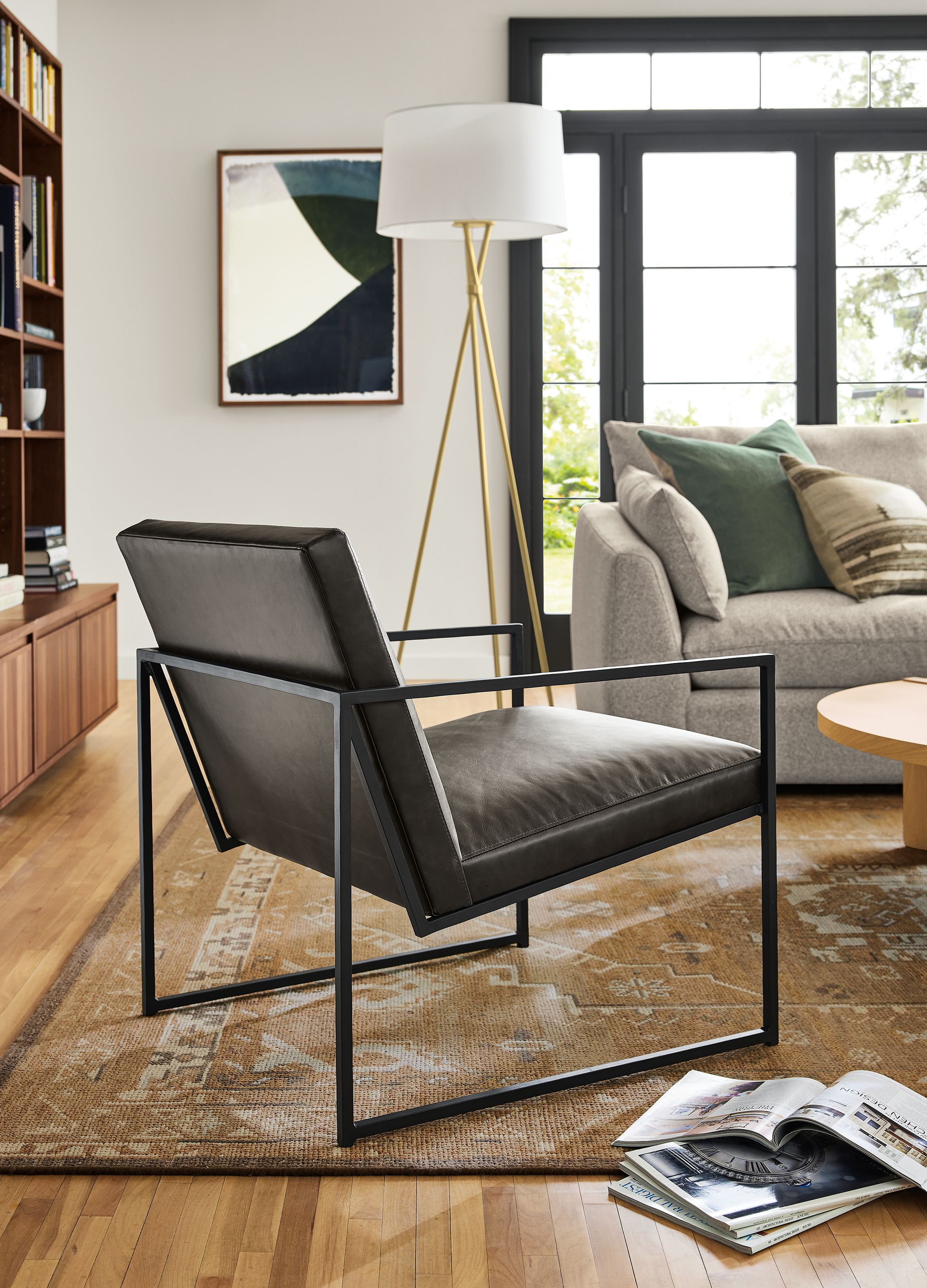 Living room with detail of Novato chair in Palermo Charcoal leather and Tri-plex floor lamp in satin brass.