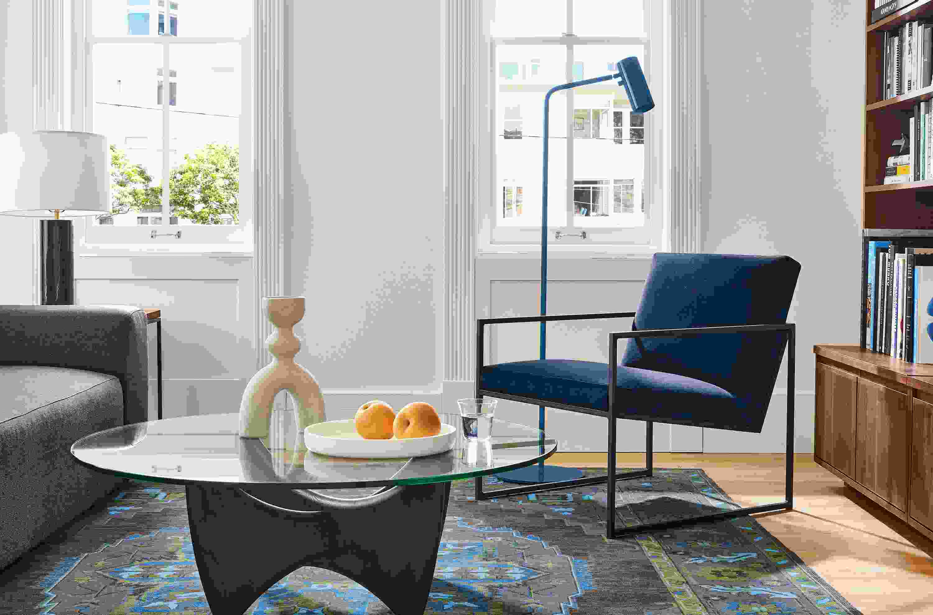 Living area with Novato chair in View Indigo fabric, Sanders coffee table in charcoal and glass and Heriz rug in ink.