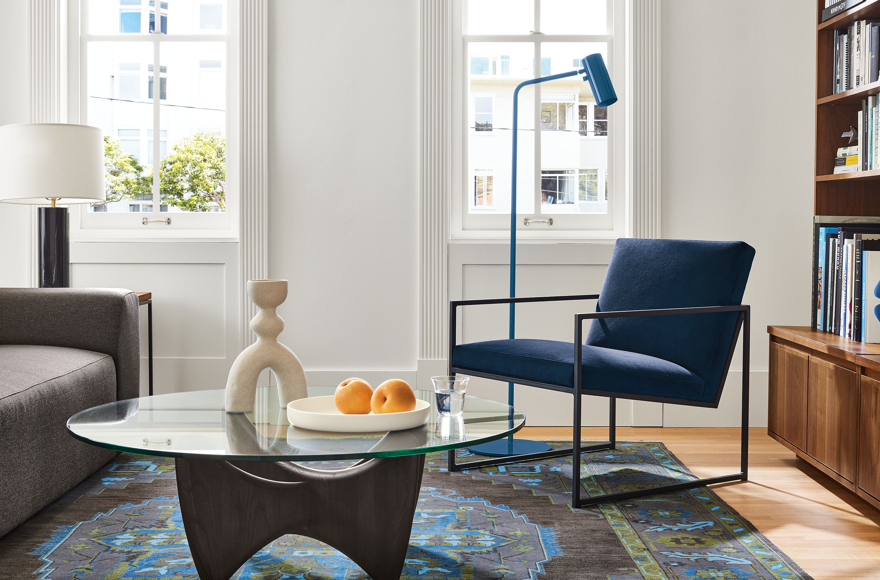 Living area with Novato chair in view indigo fabric, Sanders coffee table in charcoal and glass and Heriz rug in ink.