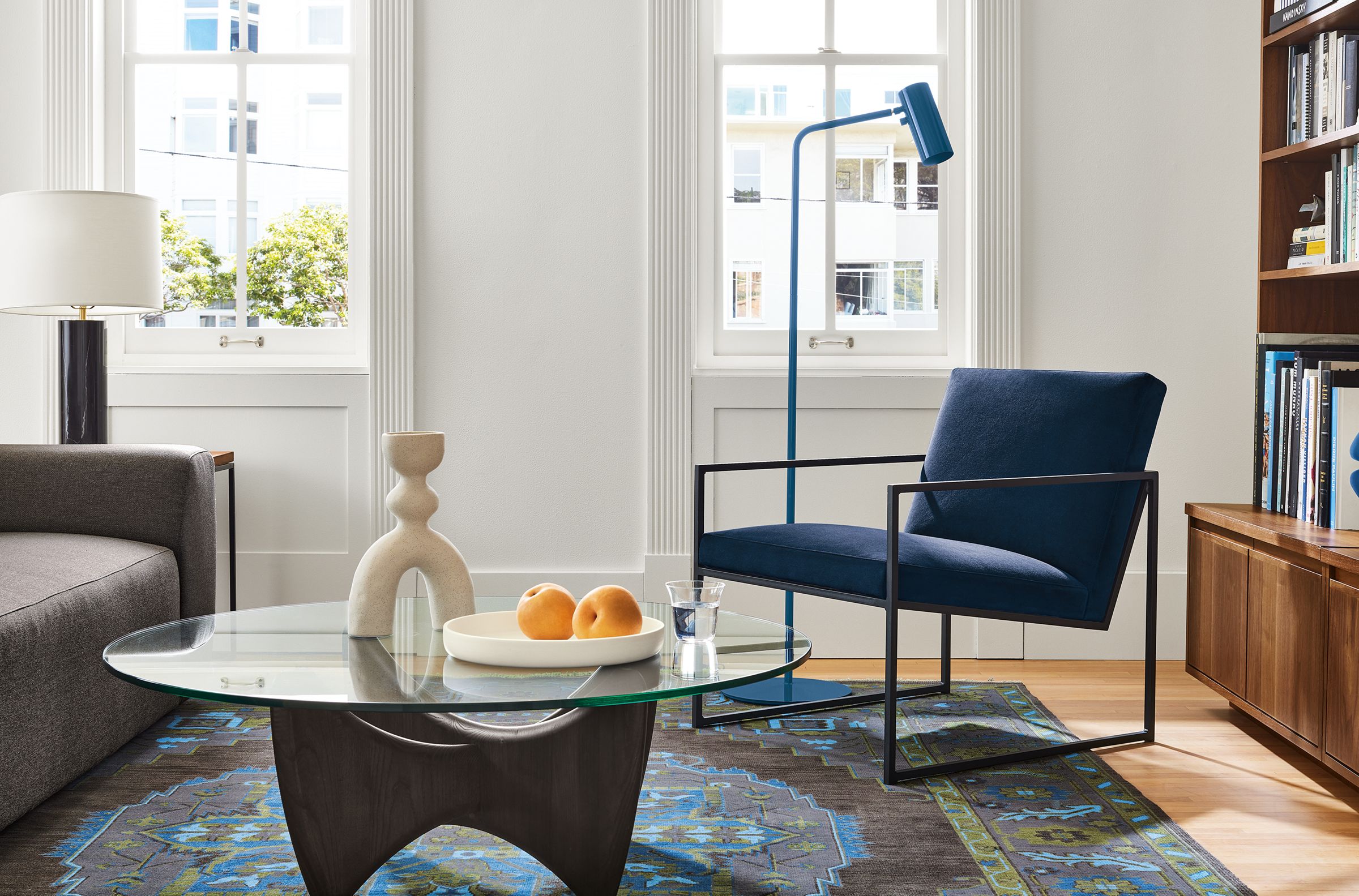 Living area with Novato chair in view indigo fabric, Sanders coffee table in charcoal and glass and Heriz rug in ink.