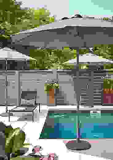 Outdoor pool setting with two Oahu round patio umbrellas and Dorian chaise in Black. 