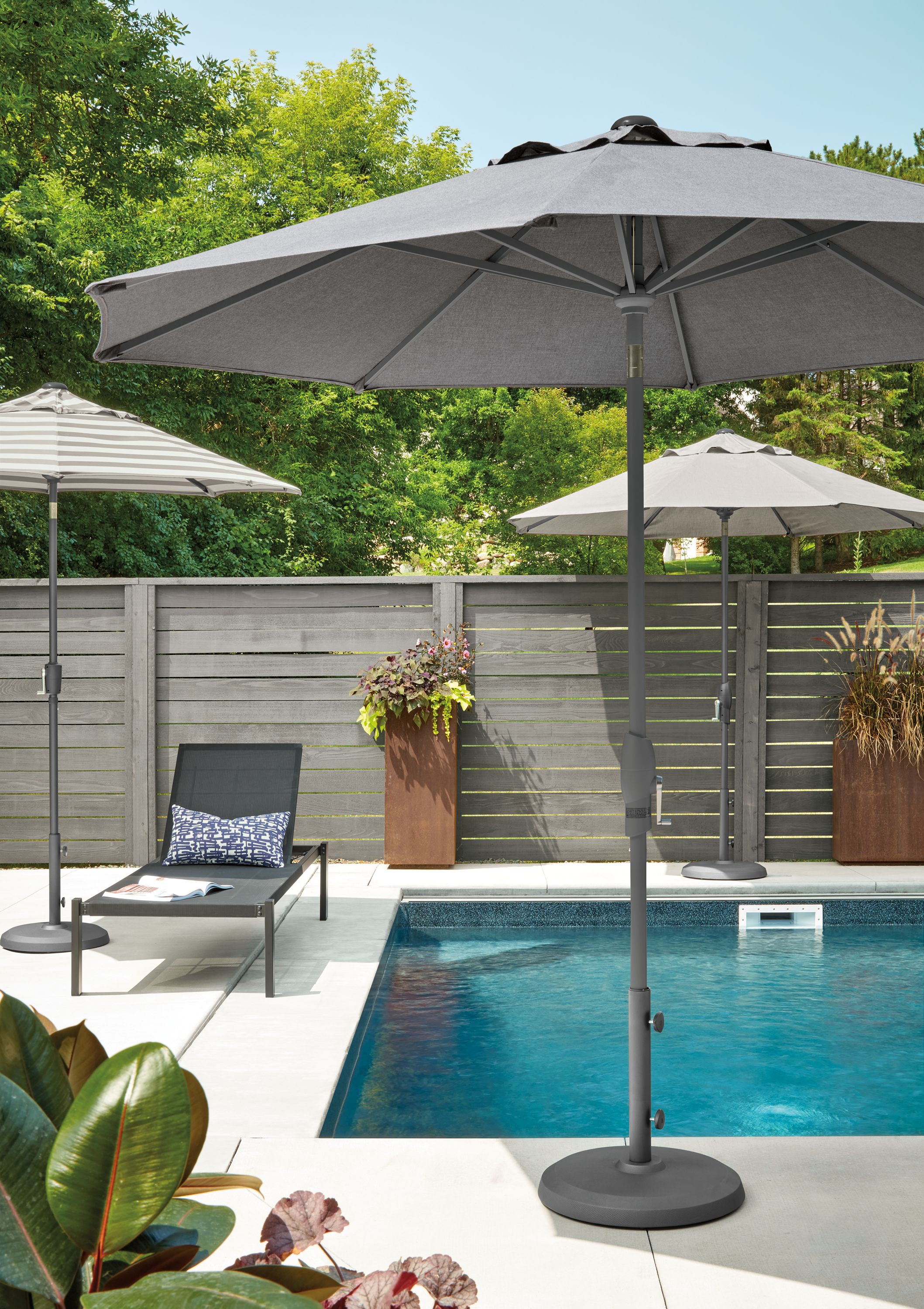 Outdoor pool setting with two Oahu round patio umbrellas and Dorian chaise in Black.