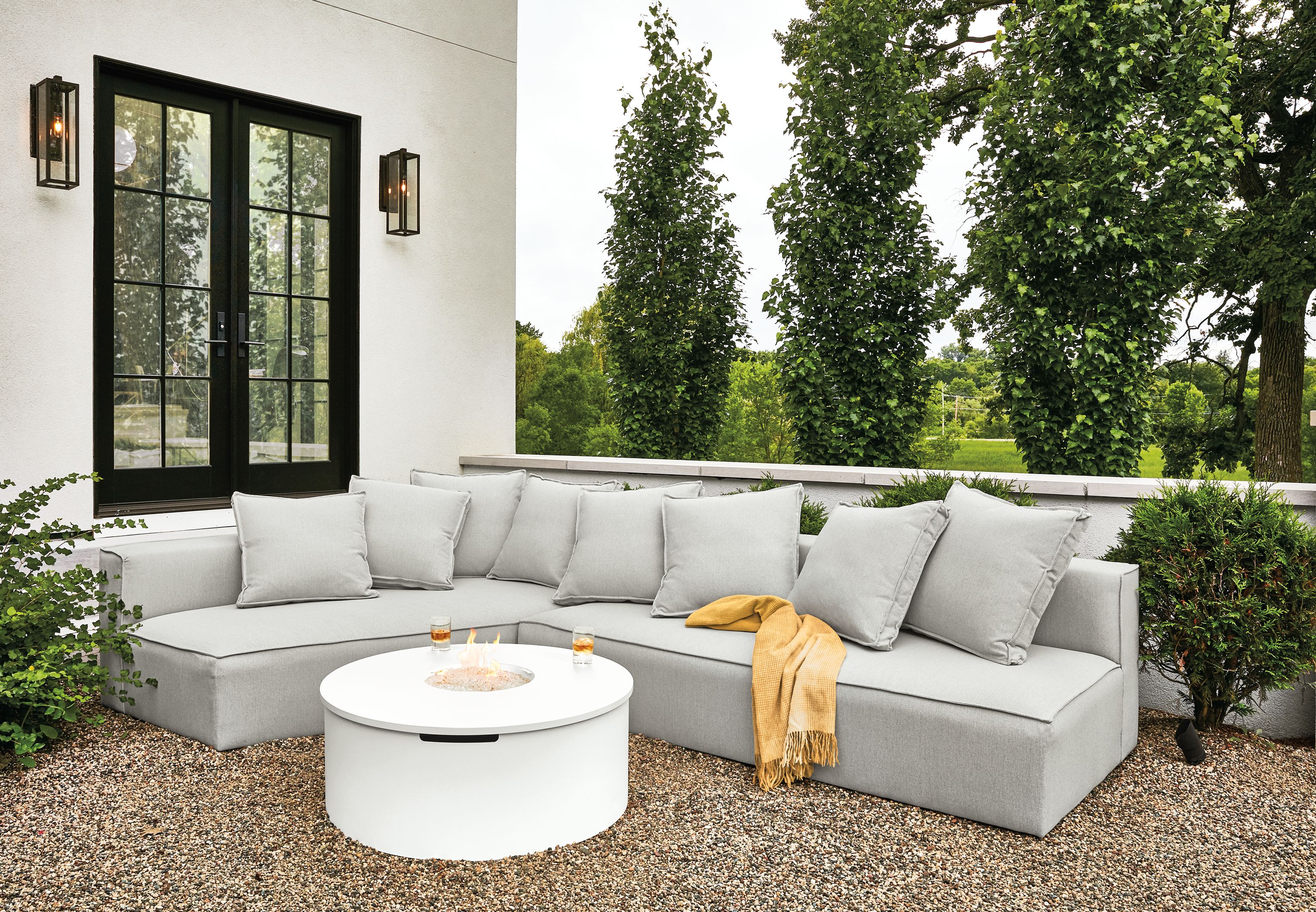 Detail of Oasis outdoor sofa in Mist grey fabric and Adara round fire table in white.