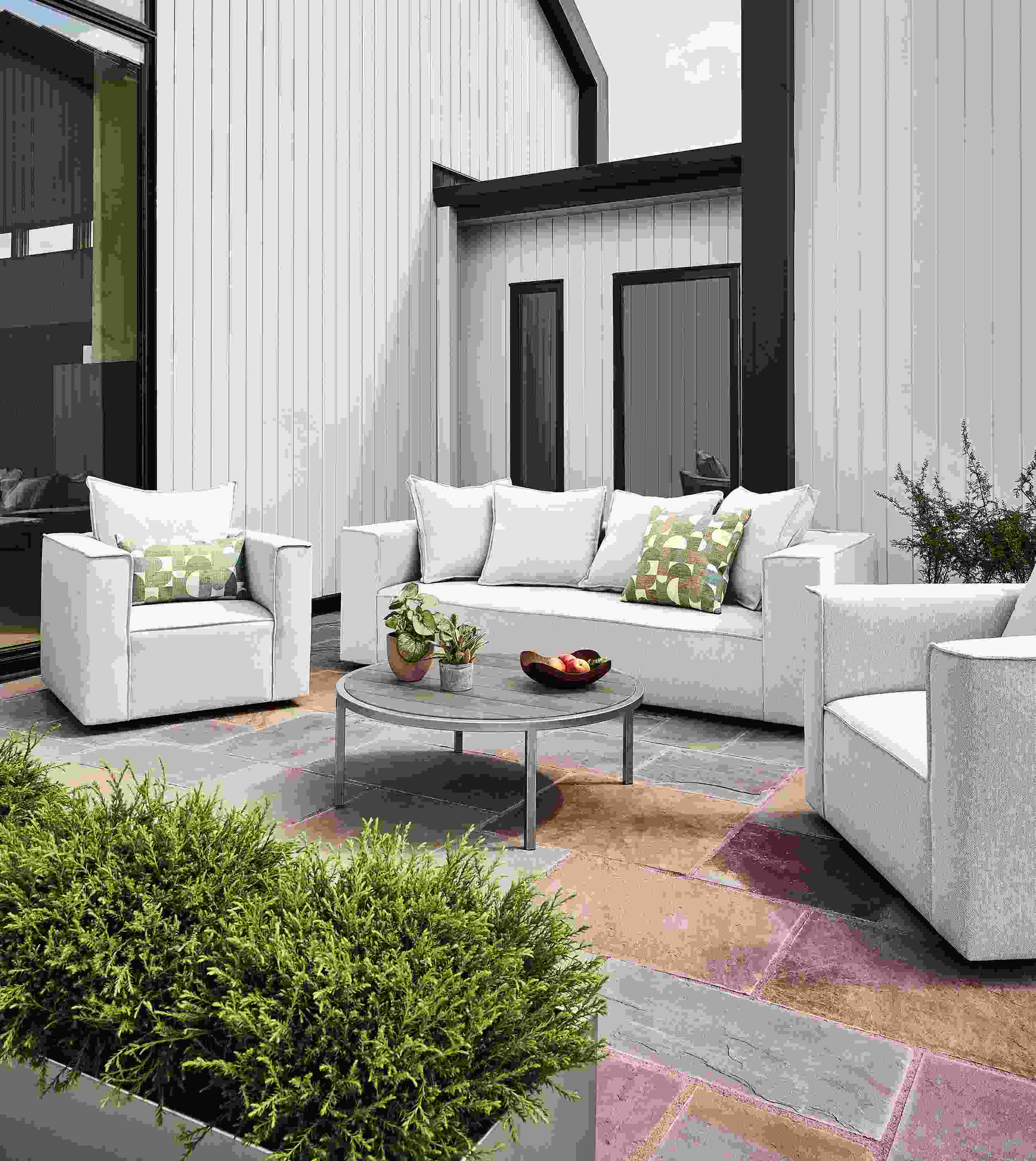 Patio with oasis sofa, 2 swivel chairs, 2 square ottomans in mist grey and a montego table in aged thermally modified oak.